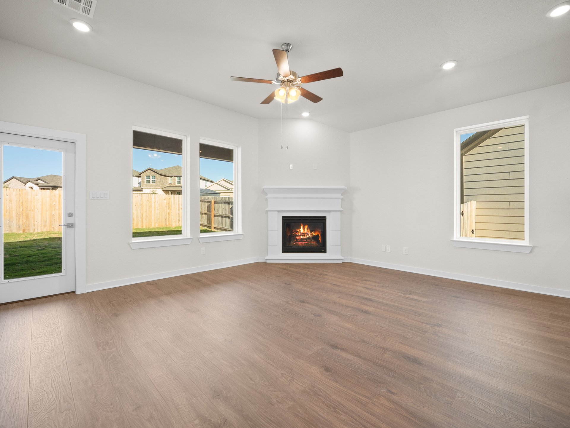 great room with brown flooring, ceiling fan & a fireplace