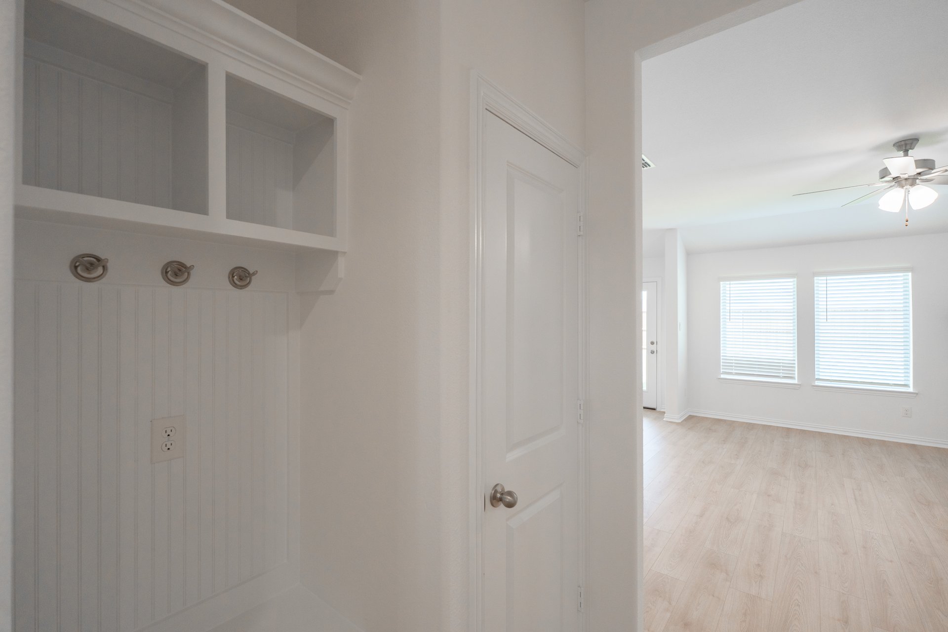 mudroom with wood floors and white shelves with bench