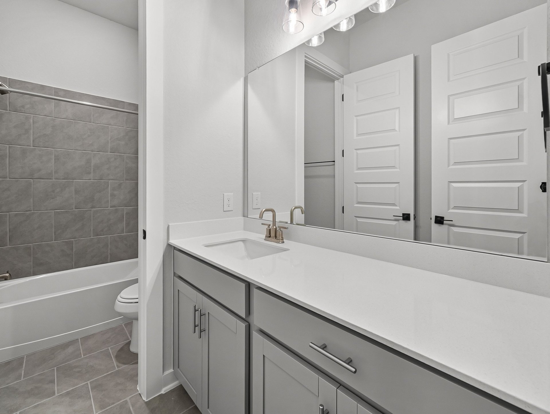 bathroom with quartz countertops & a tub with shower combo
