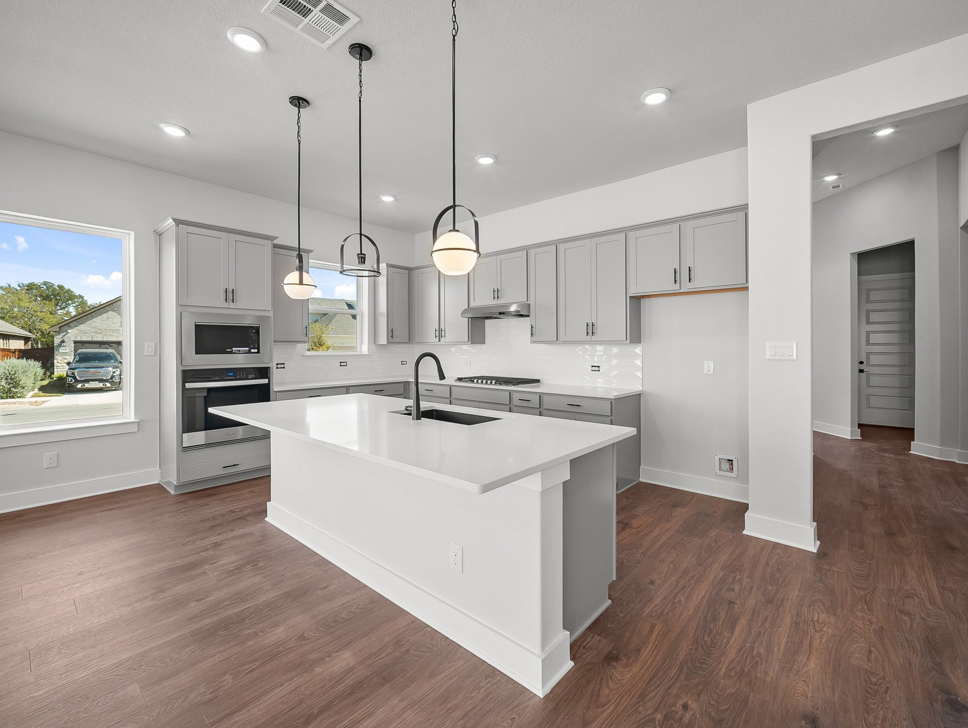 kitchen with quartz countertops, brown flooring & pendant lighting
