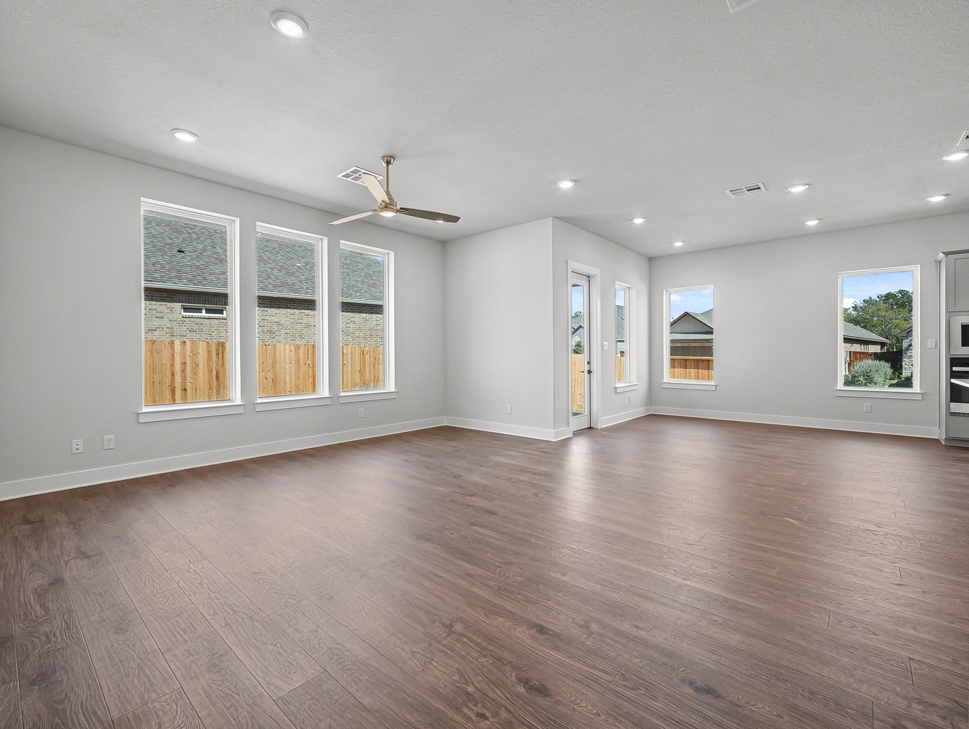 great room with brown flooring, windows & a ceiling fan