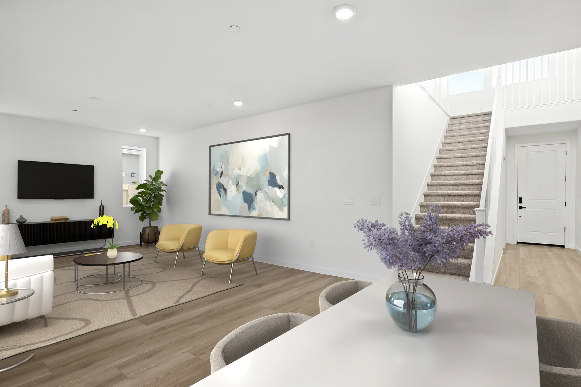 great room with wood floors, two yellow accent chairs, television on wall, and modern wall art