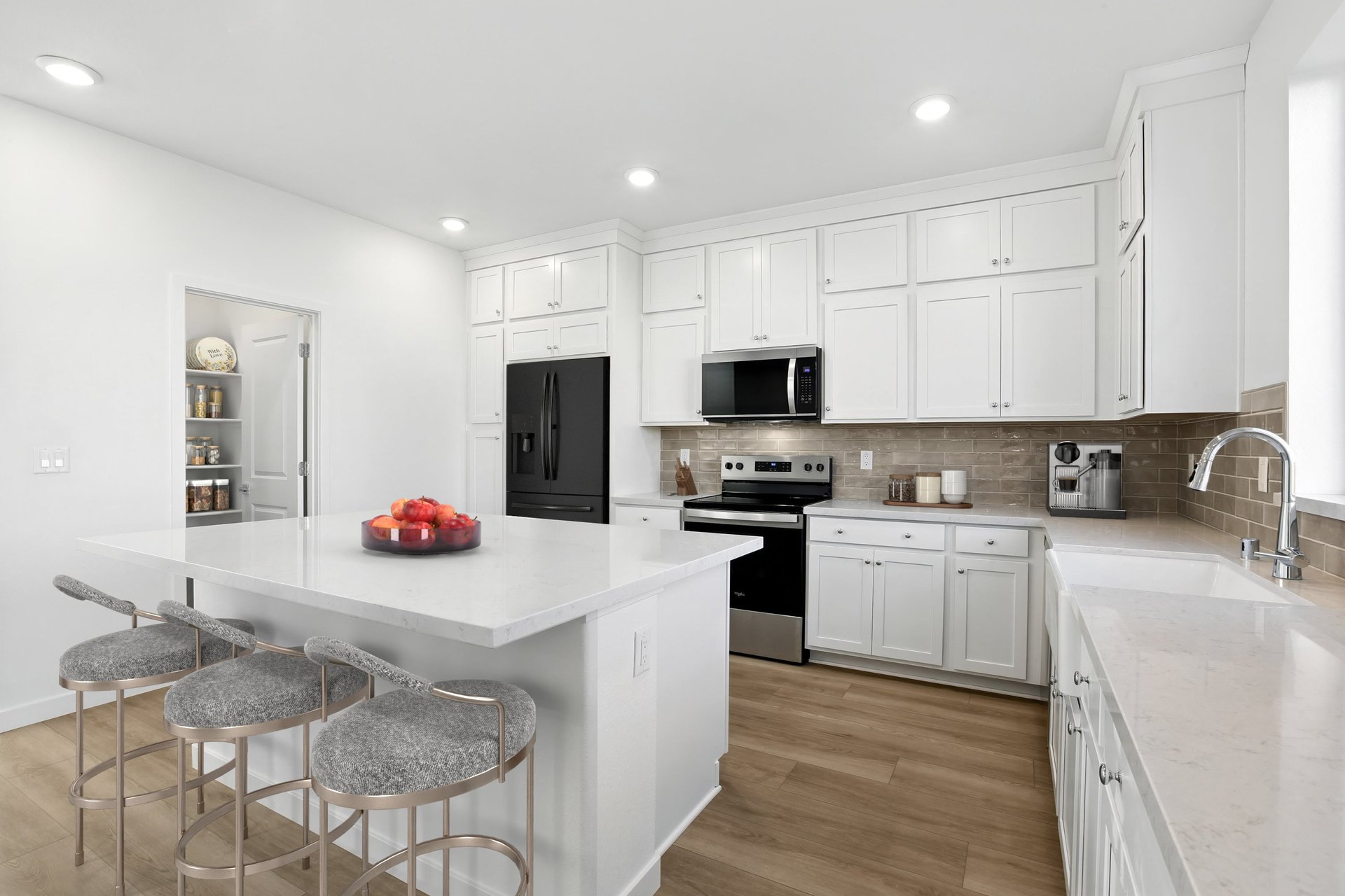 kitchen with wood floors, white cabinets & counters, tan tile backsplash, island, and walk-in pantry with shelves