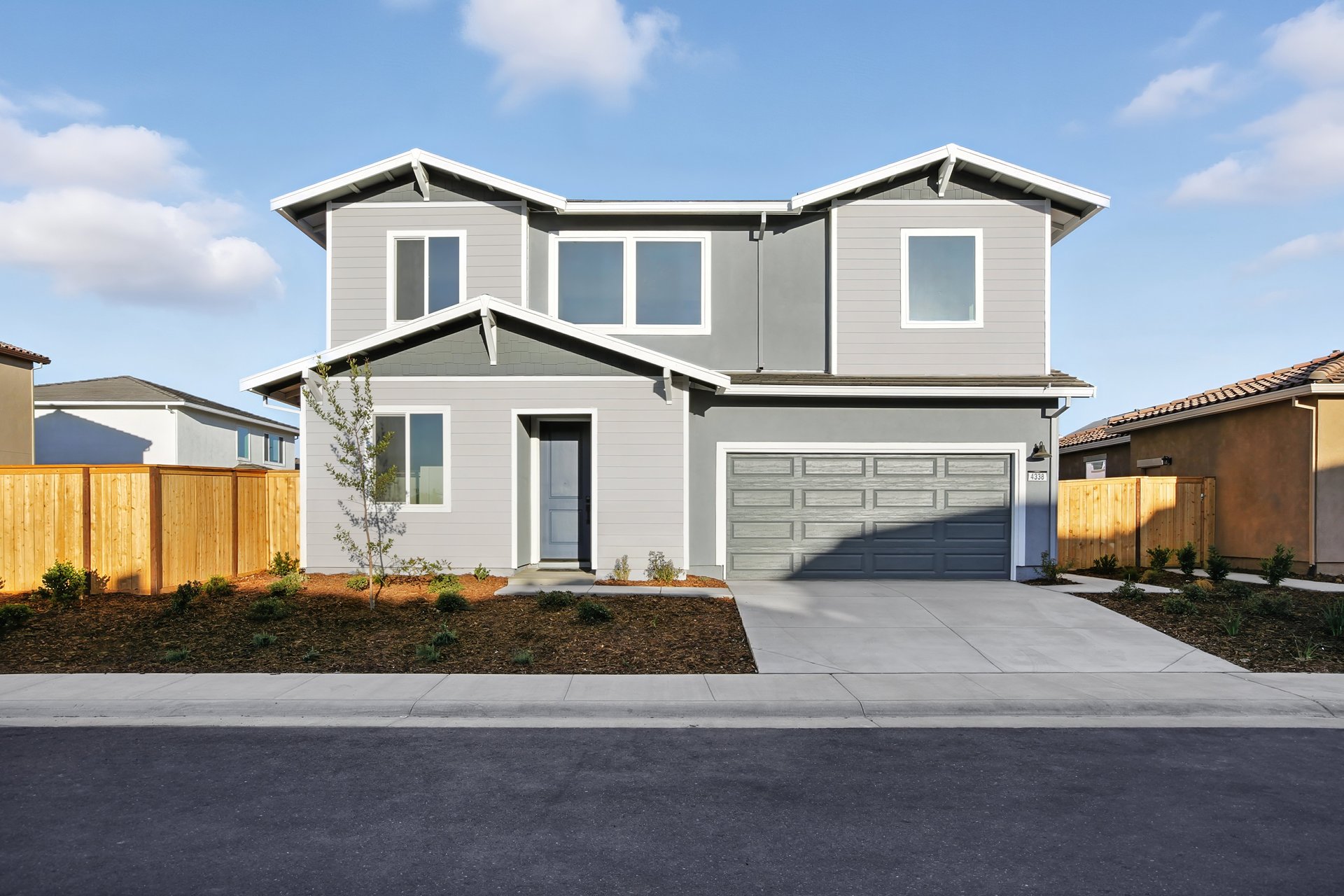 front exterior of two-story gray & white home with 2-car garage, and drought resistant landscaping