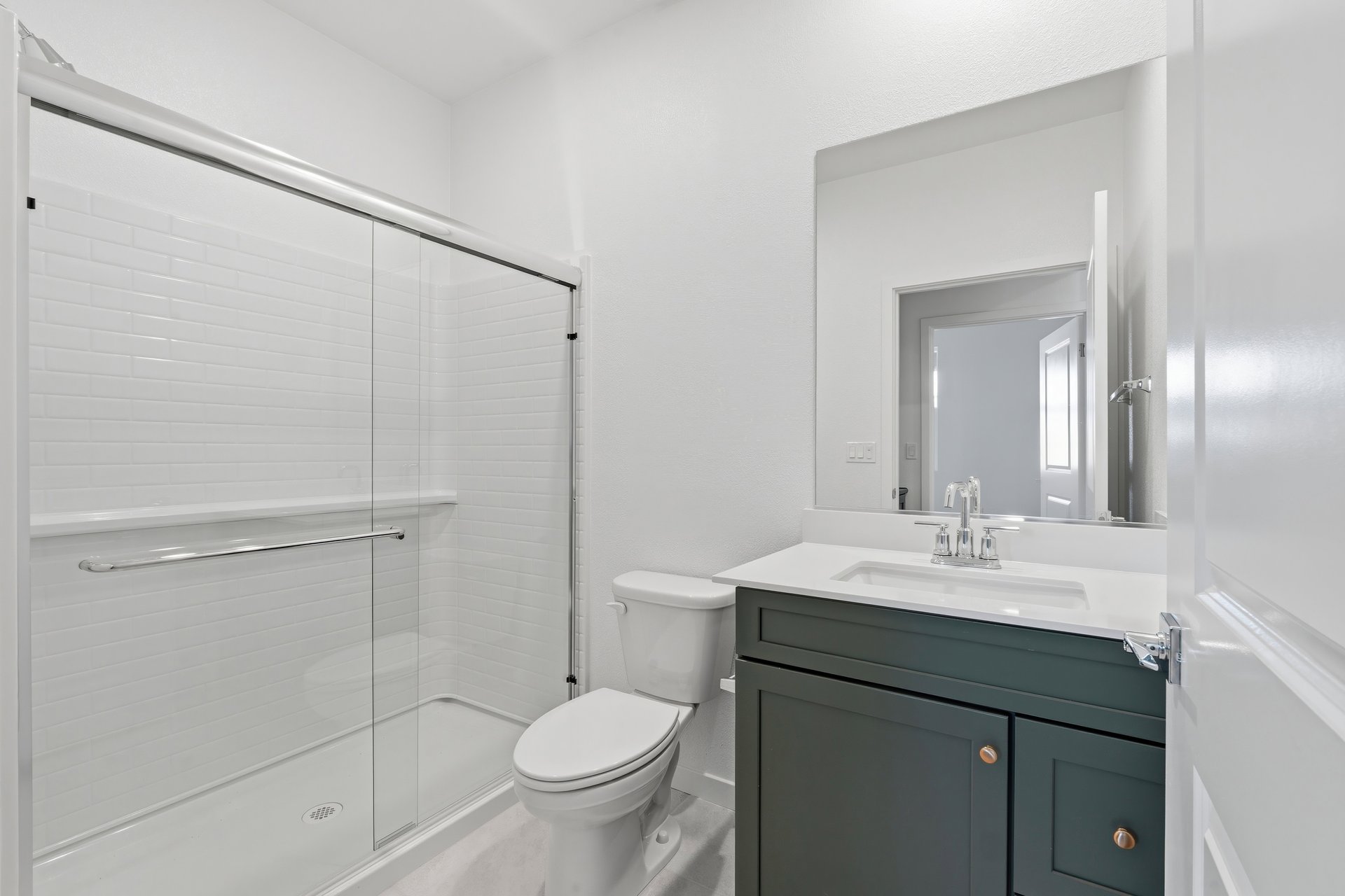bathroom with green cabinets, white counter, and large walk-in shower
