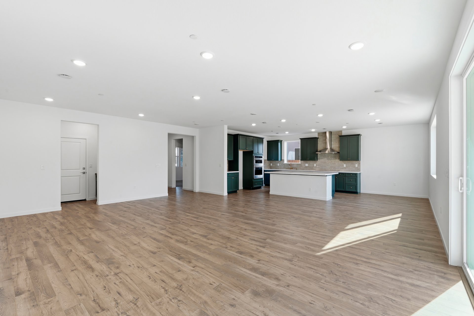 large great room with wood floors, white walls, recessed ceiling lights, and view of kitchen