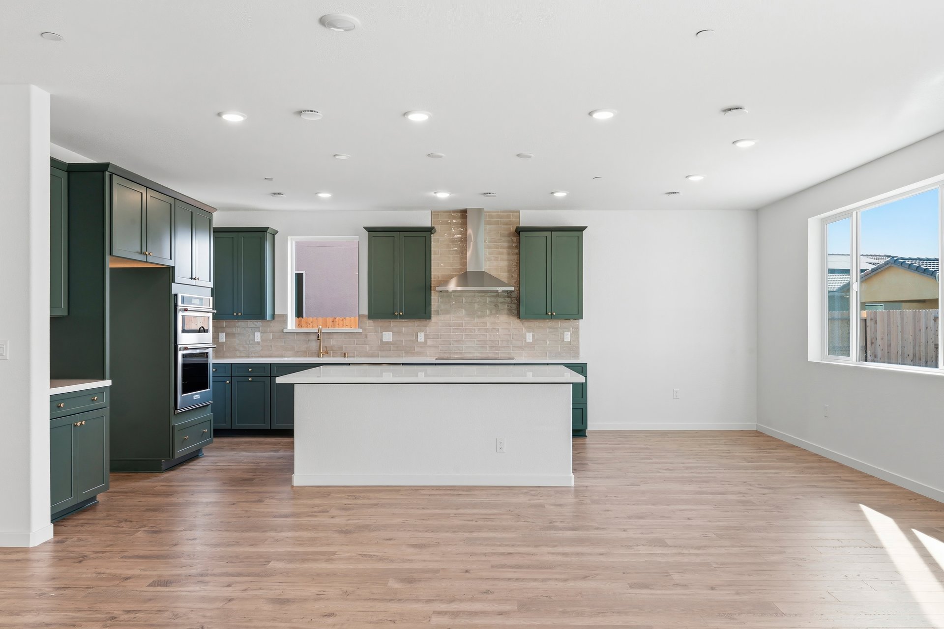 kitchen with green cabinets, white counters, island, wood floors, and two windows