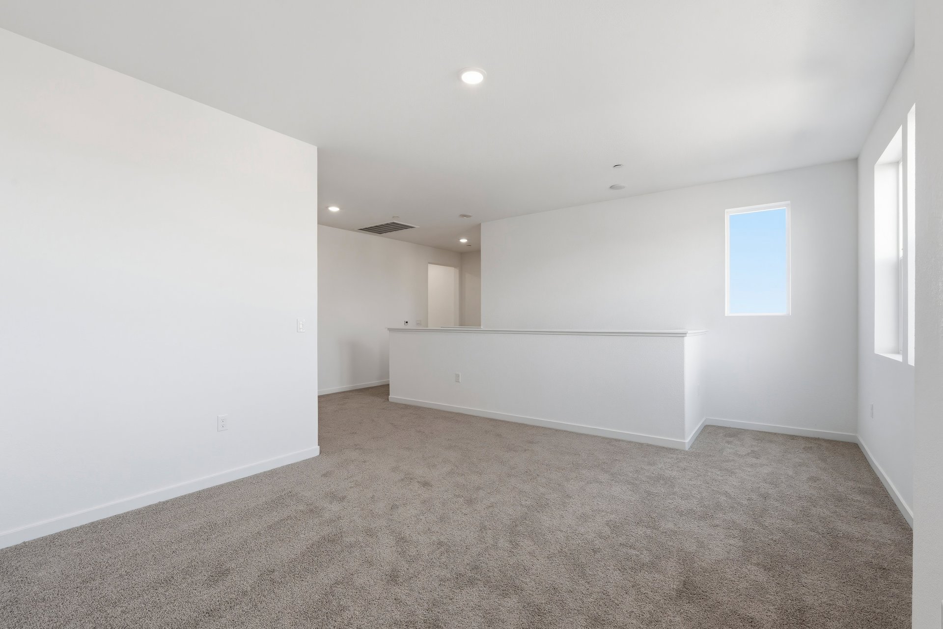 loft with tan carpet, white walls, windows, and recessed ceiling lights