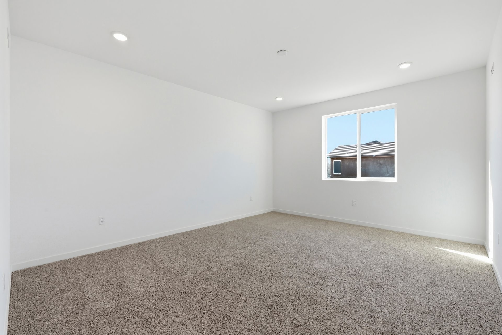 bedroom with tan carpet, window, white walls, and recessed ceiling lights