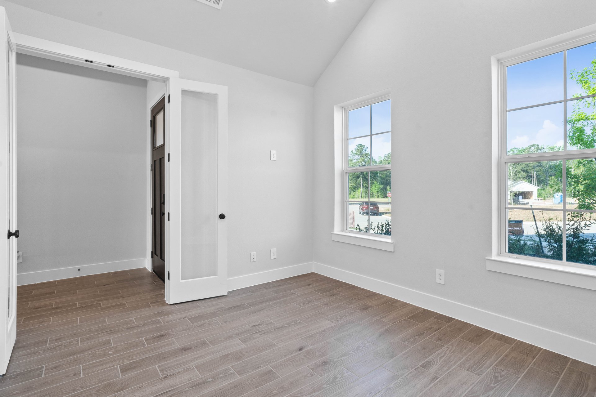 spacious study with wood-look tile flooring and double doors