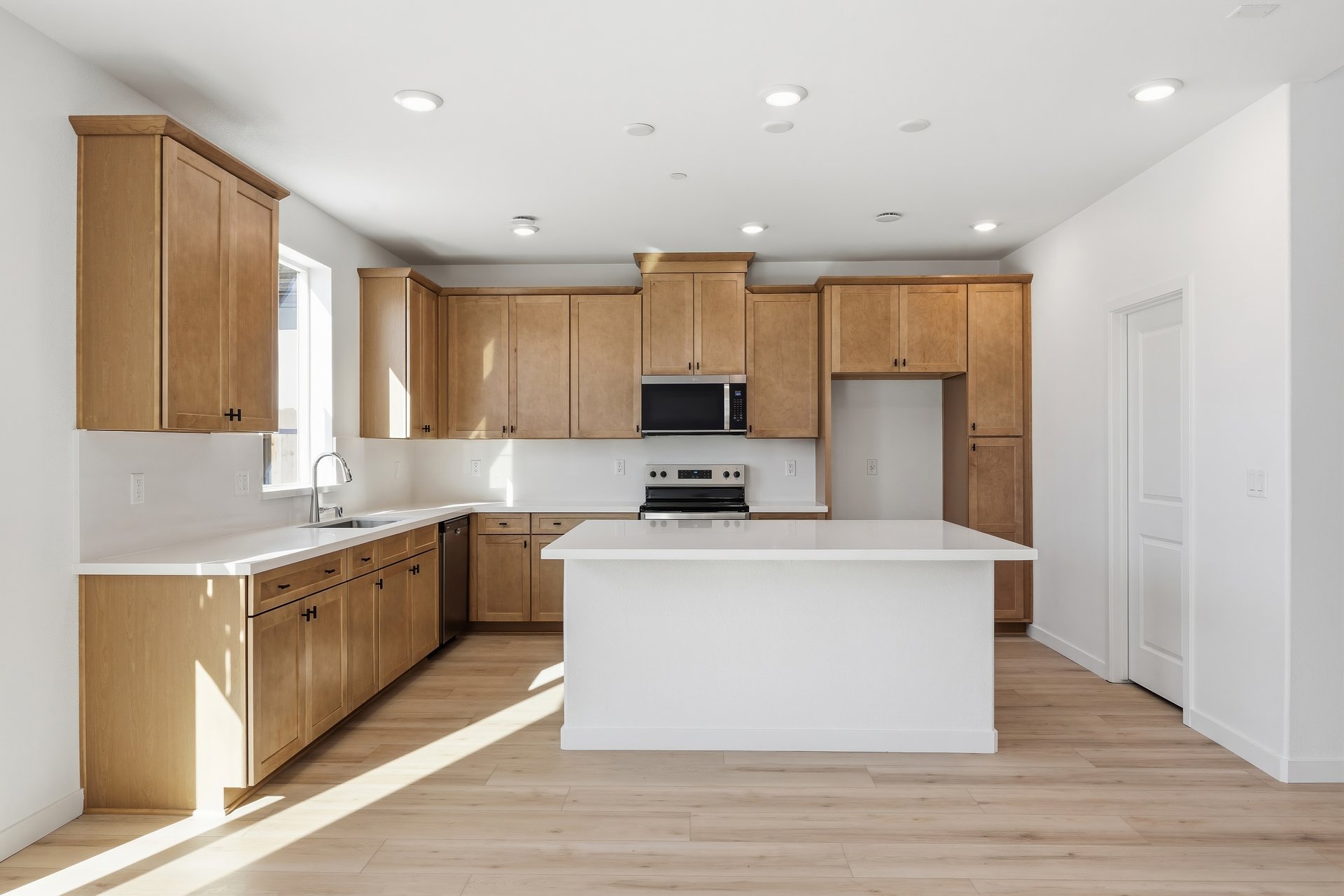 kitchen with light wood cabinets, white counters, center island, wood floors, and window