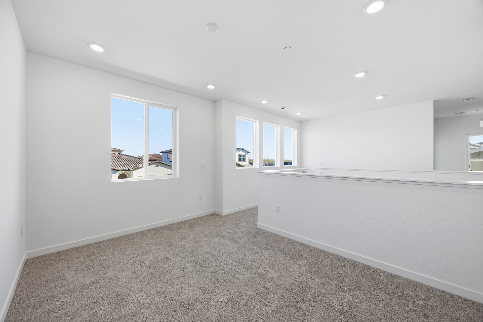 loft with gray carpet, white walls, and multiple windows