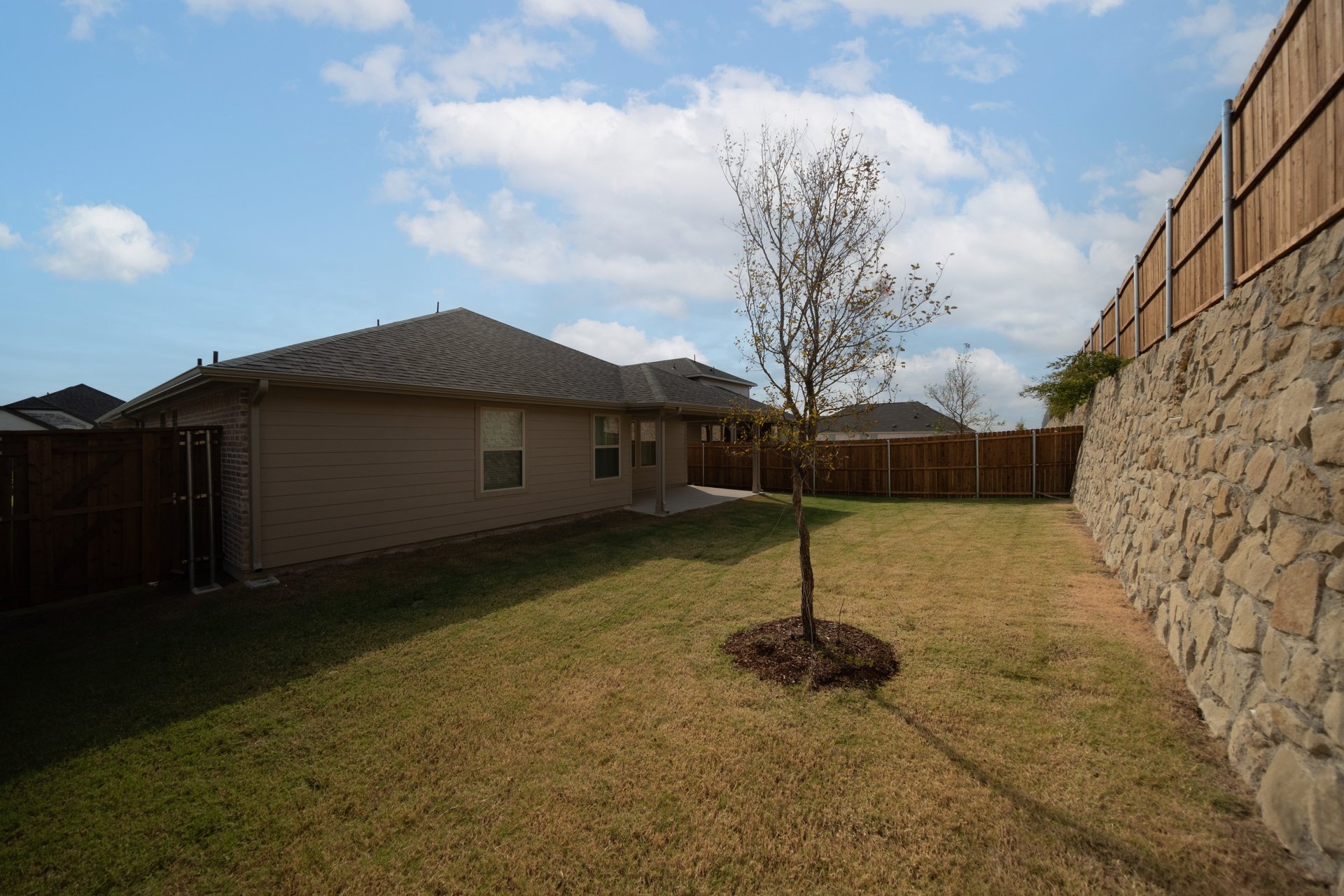 backyard with stone wall and covered patio