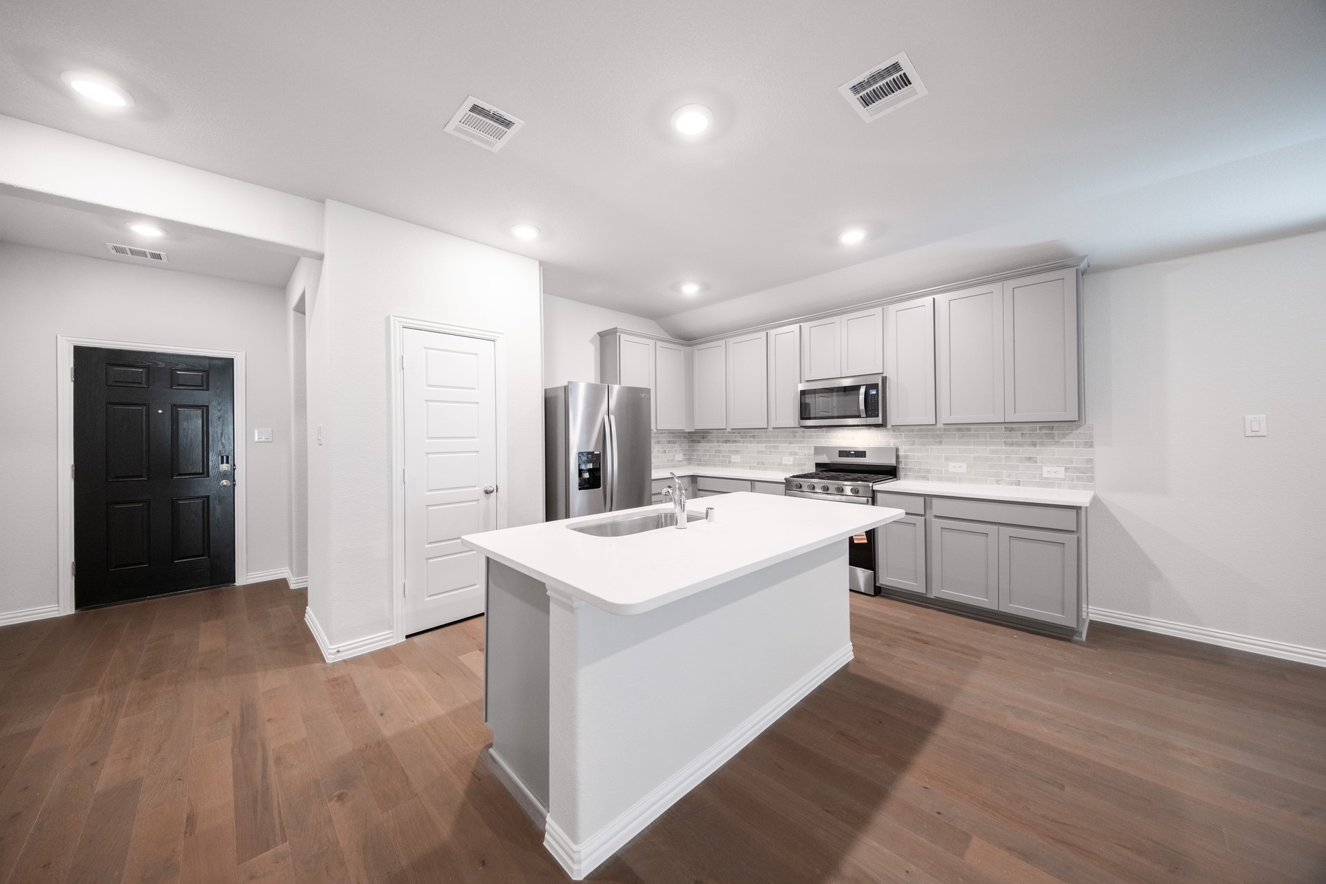 open kitchen with wood floors and white cabinets