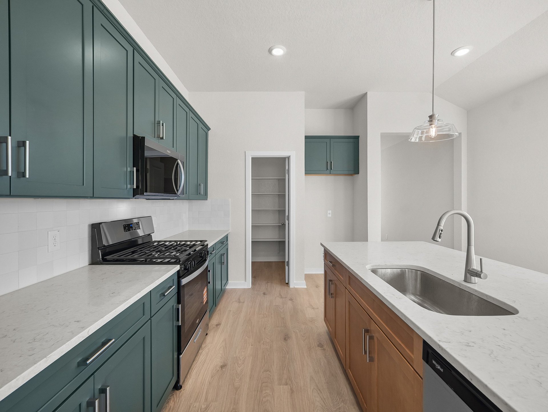 kitchen with pendant lighting, green cabinets & an island sink