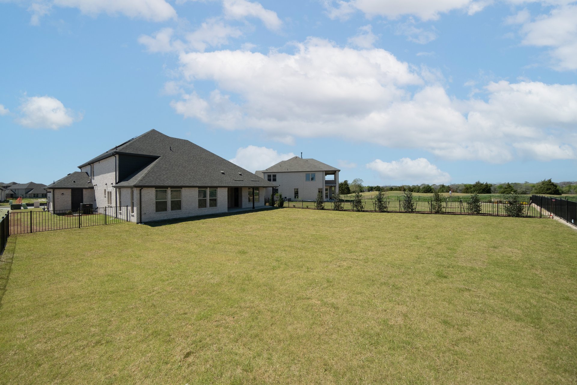 backyard of home with grass and iron fencing