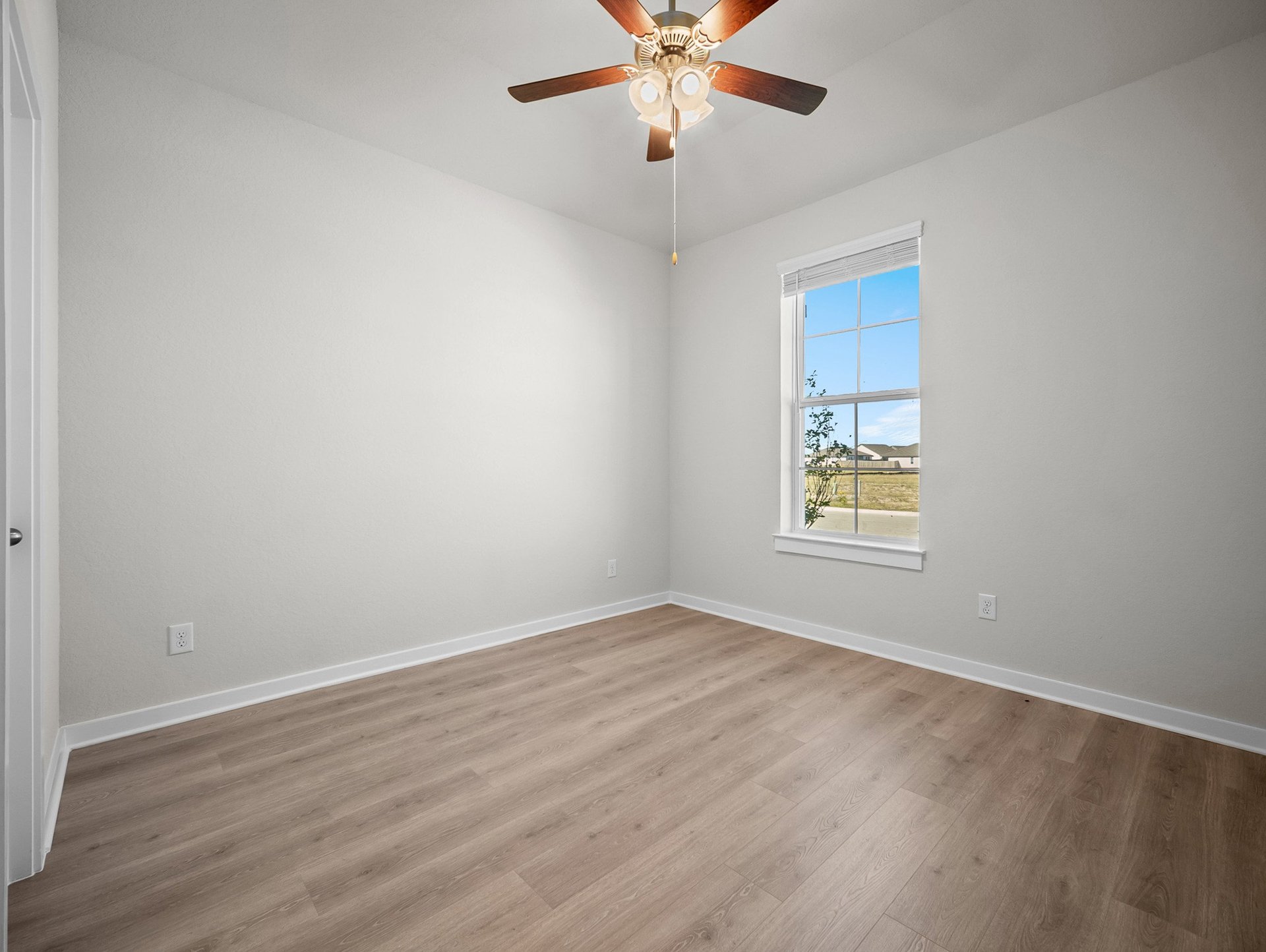 bedroom with brown flooring, a window & a ceiling fan