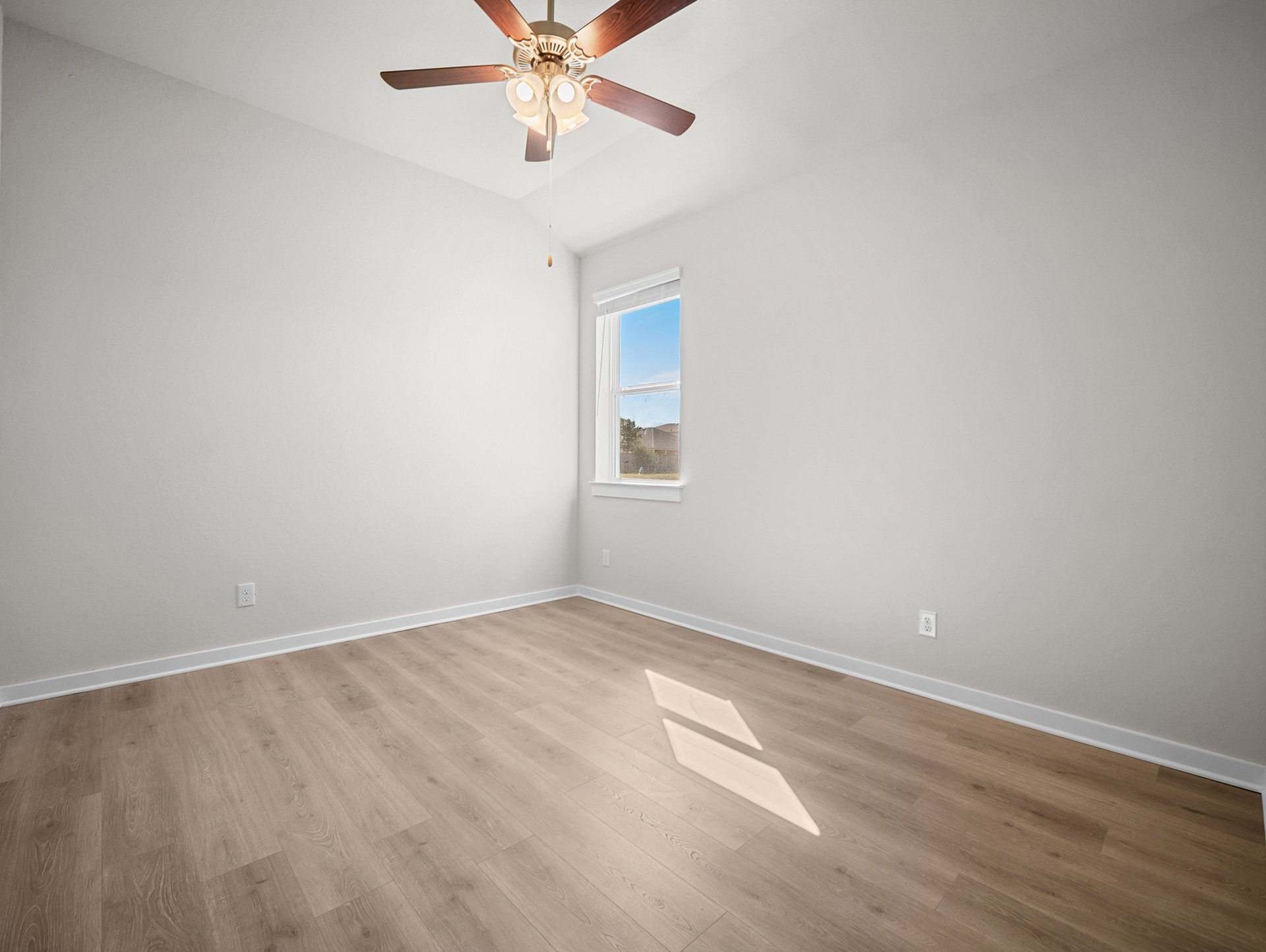 bedroom with brown flooring, a window & a ceiling fan
