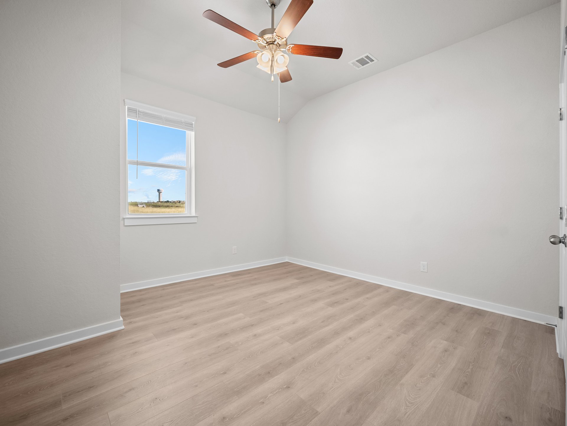 bedroom with brown flooring, window & a ceiling fan