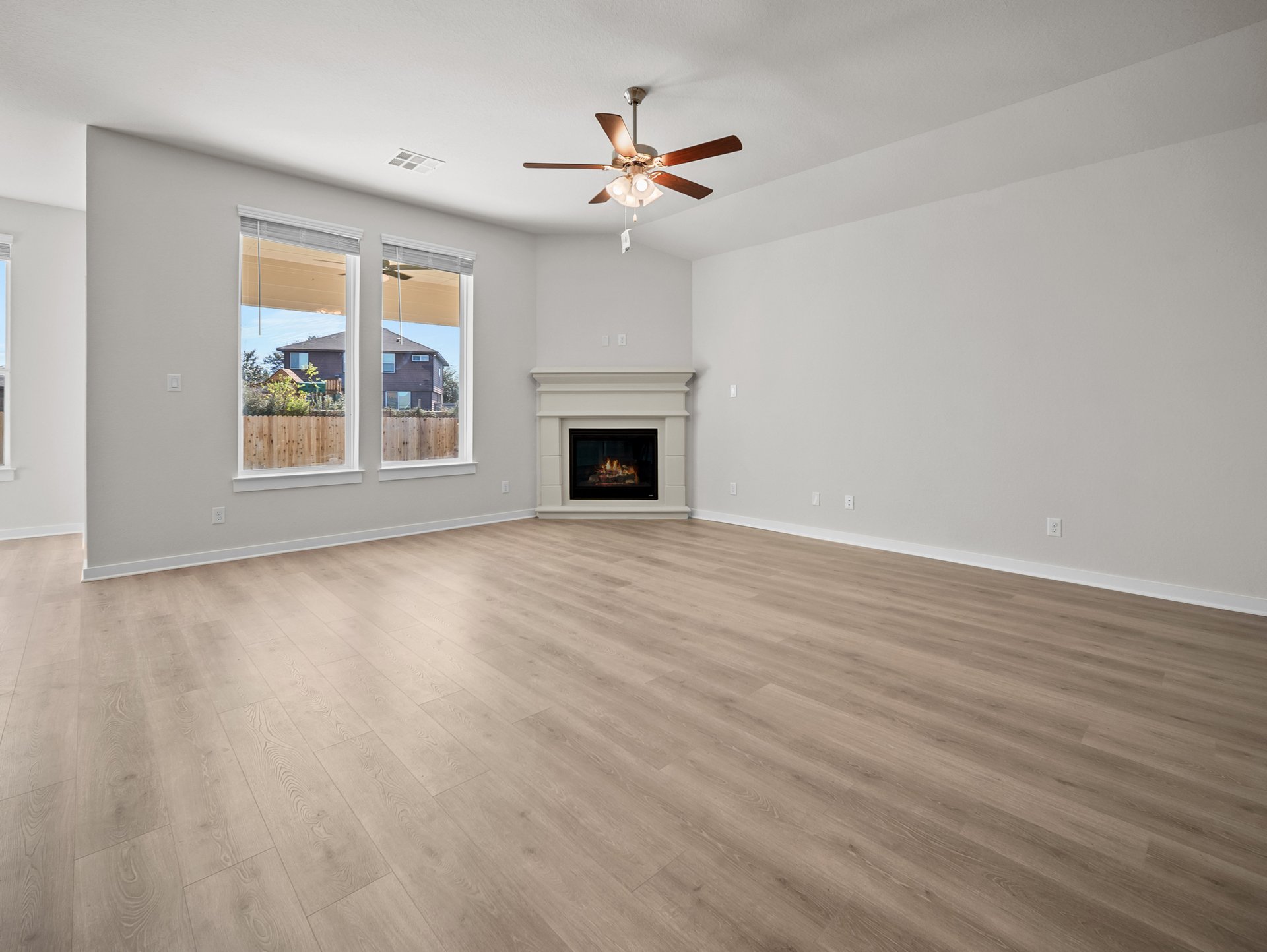 great room with brown flooring, fireplace & a ceiling fan