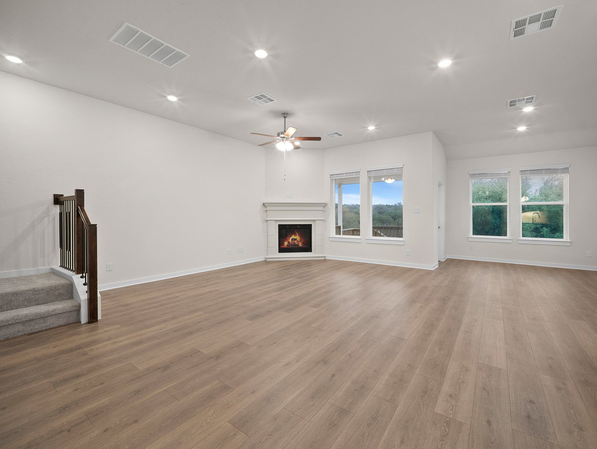 great room with brown flooring, ceiling fan & a fireplace