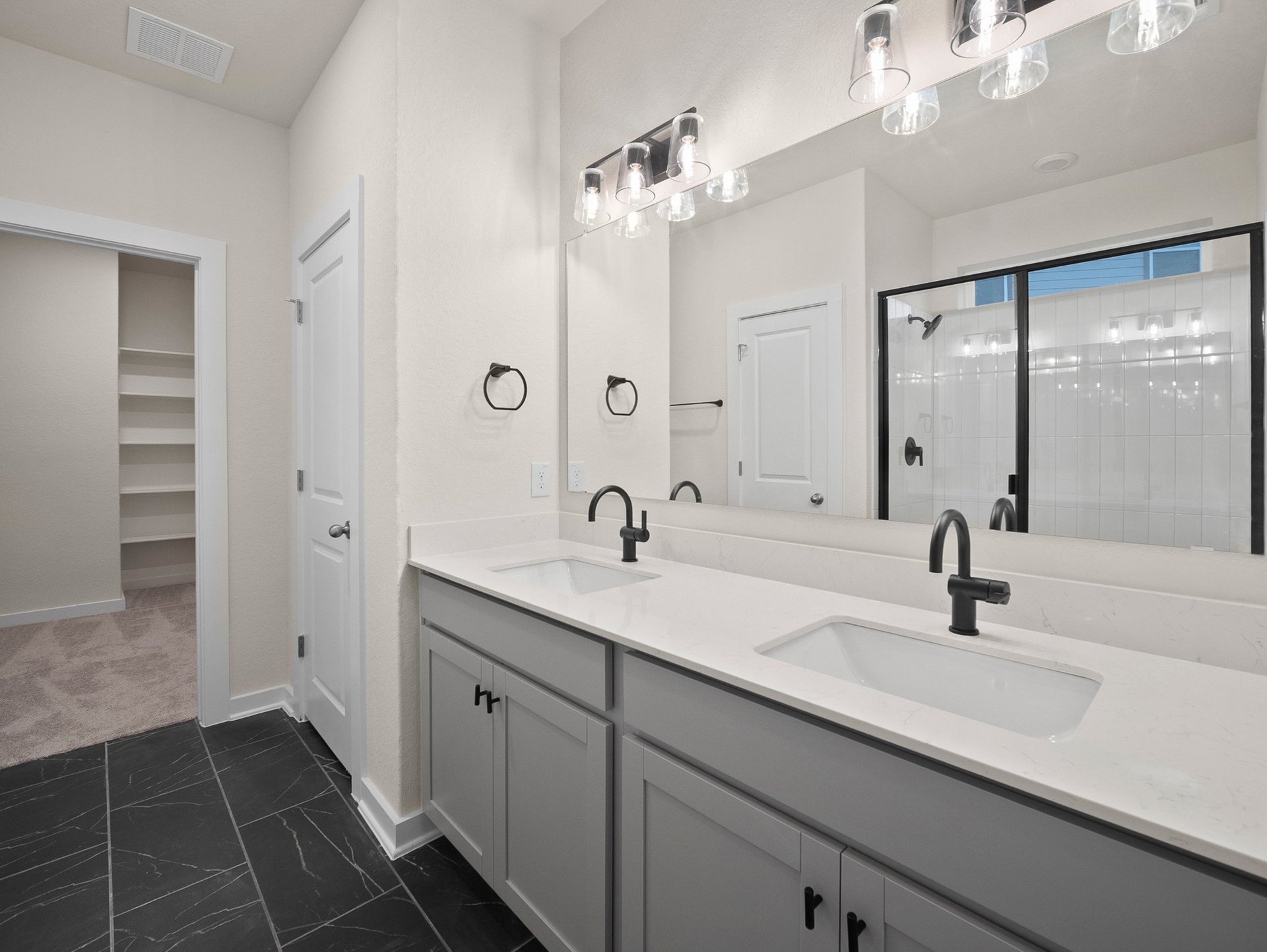 bathroom with dual sinks, tile flooring & a walk-in shower