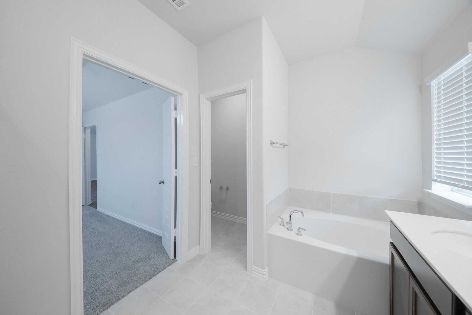 primary bathroom with soaking tub and tile floors 