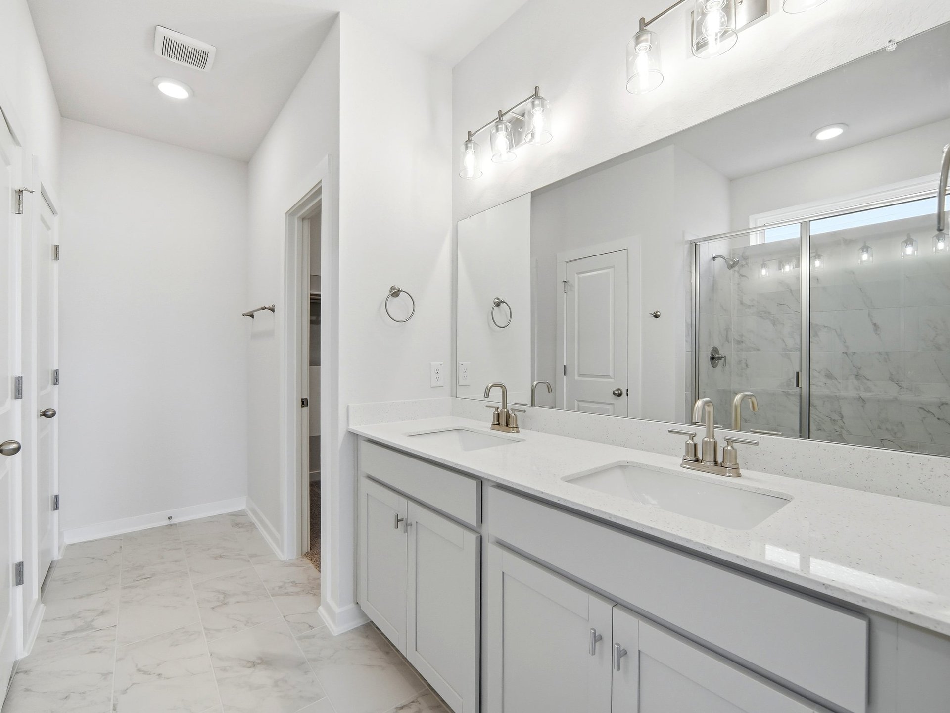 primary bath with dual sinks, white tile and pendant lighting