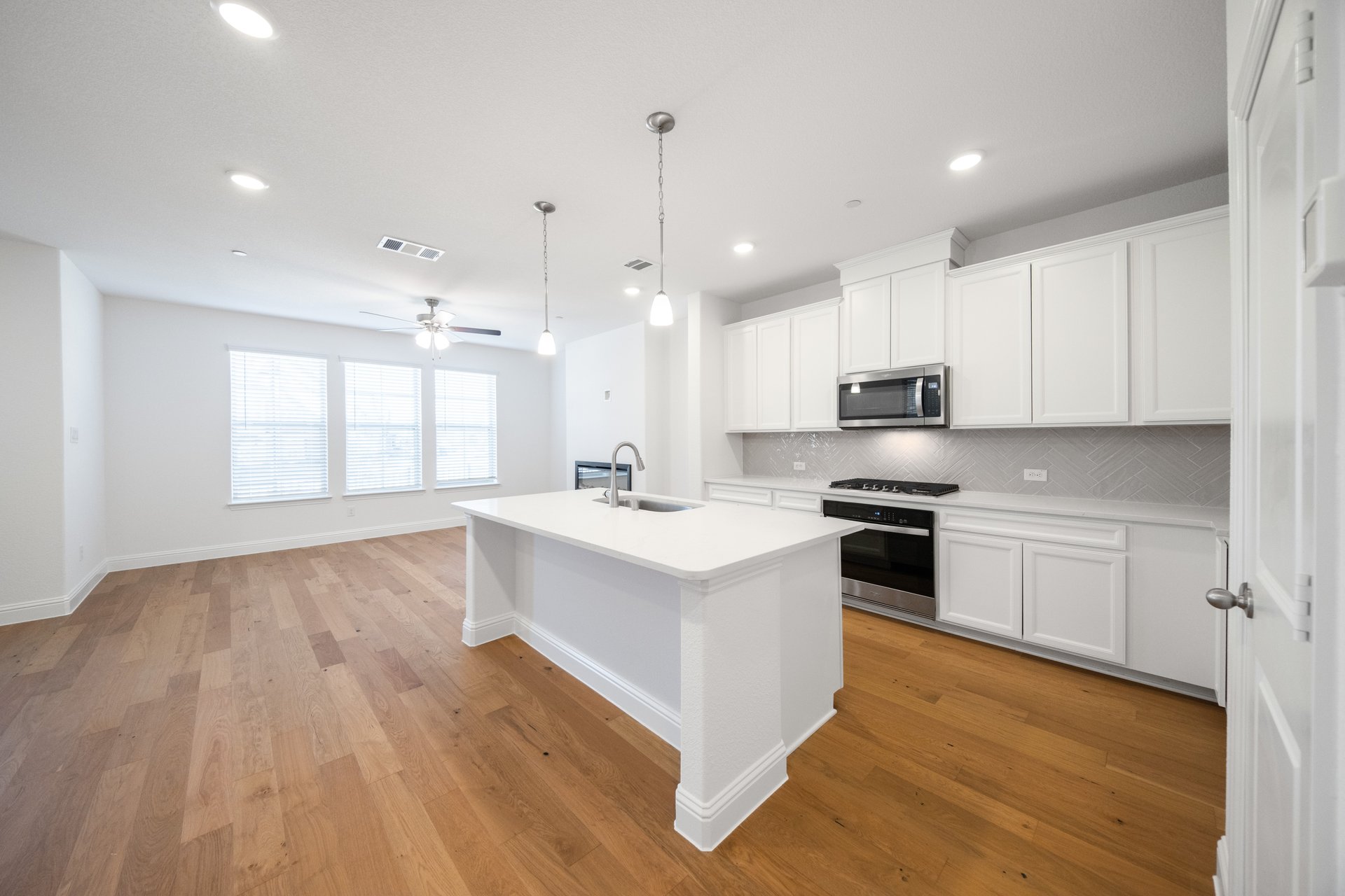 open kitchen with wood floors and white cabinets