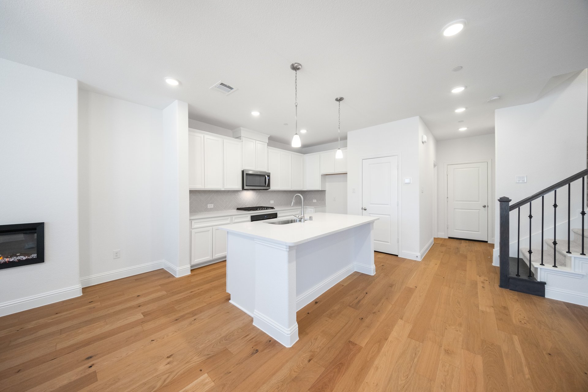 open kitchen with wood floors and white cabinets