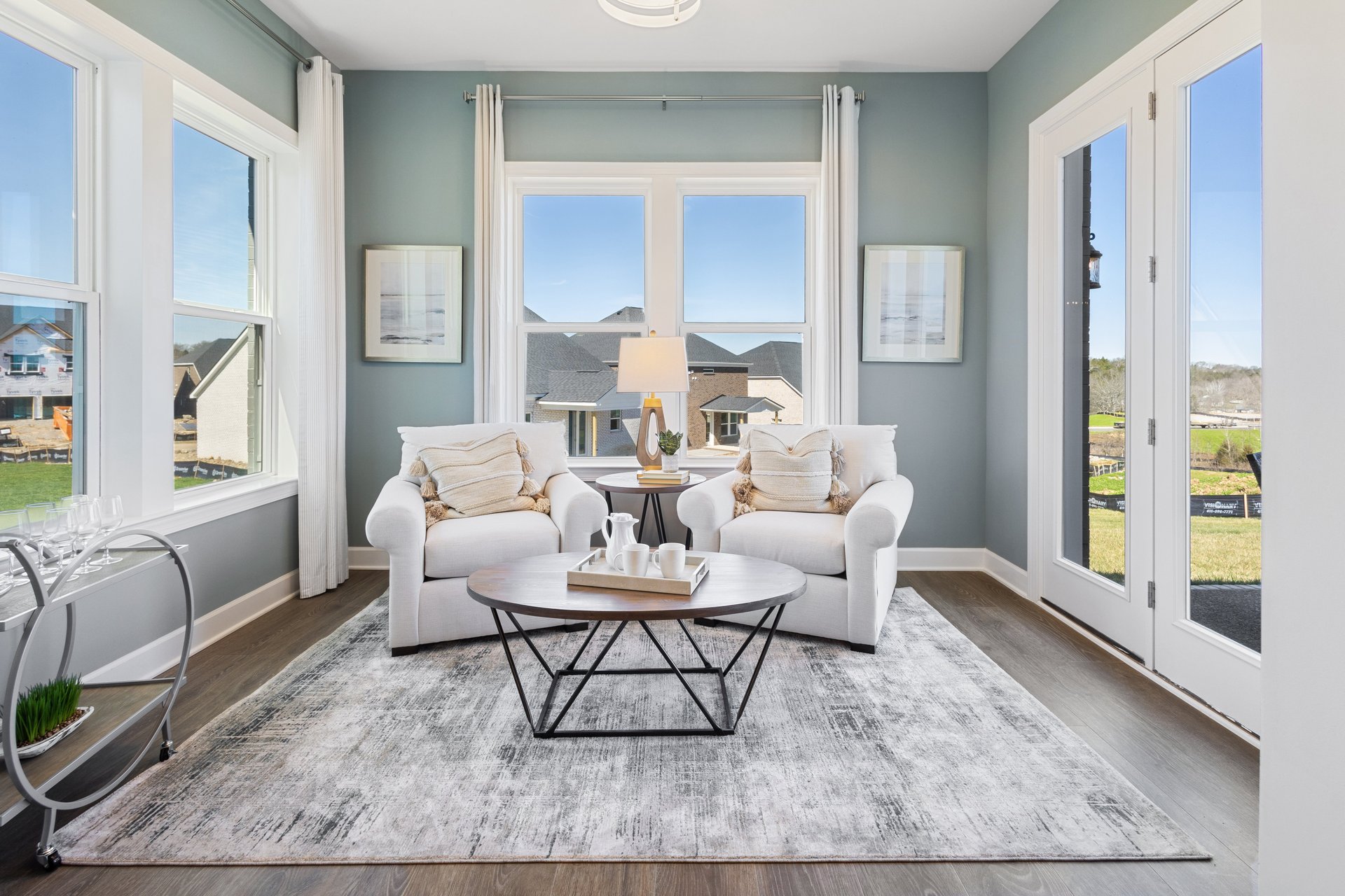 morning room with hardwood floors, two white cushioned chairs, and a round coffee table