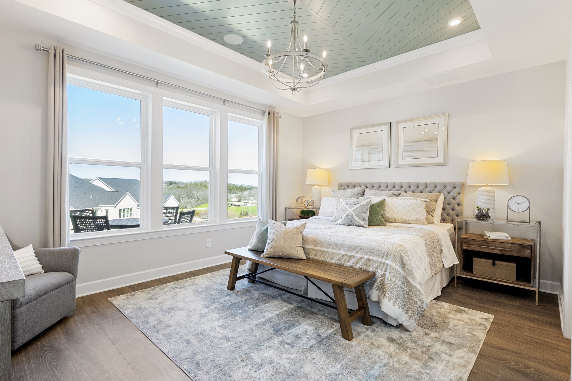 primary bedroom with hardwood floors, a tray ceiling, and a queen-size bed