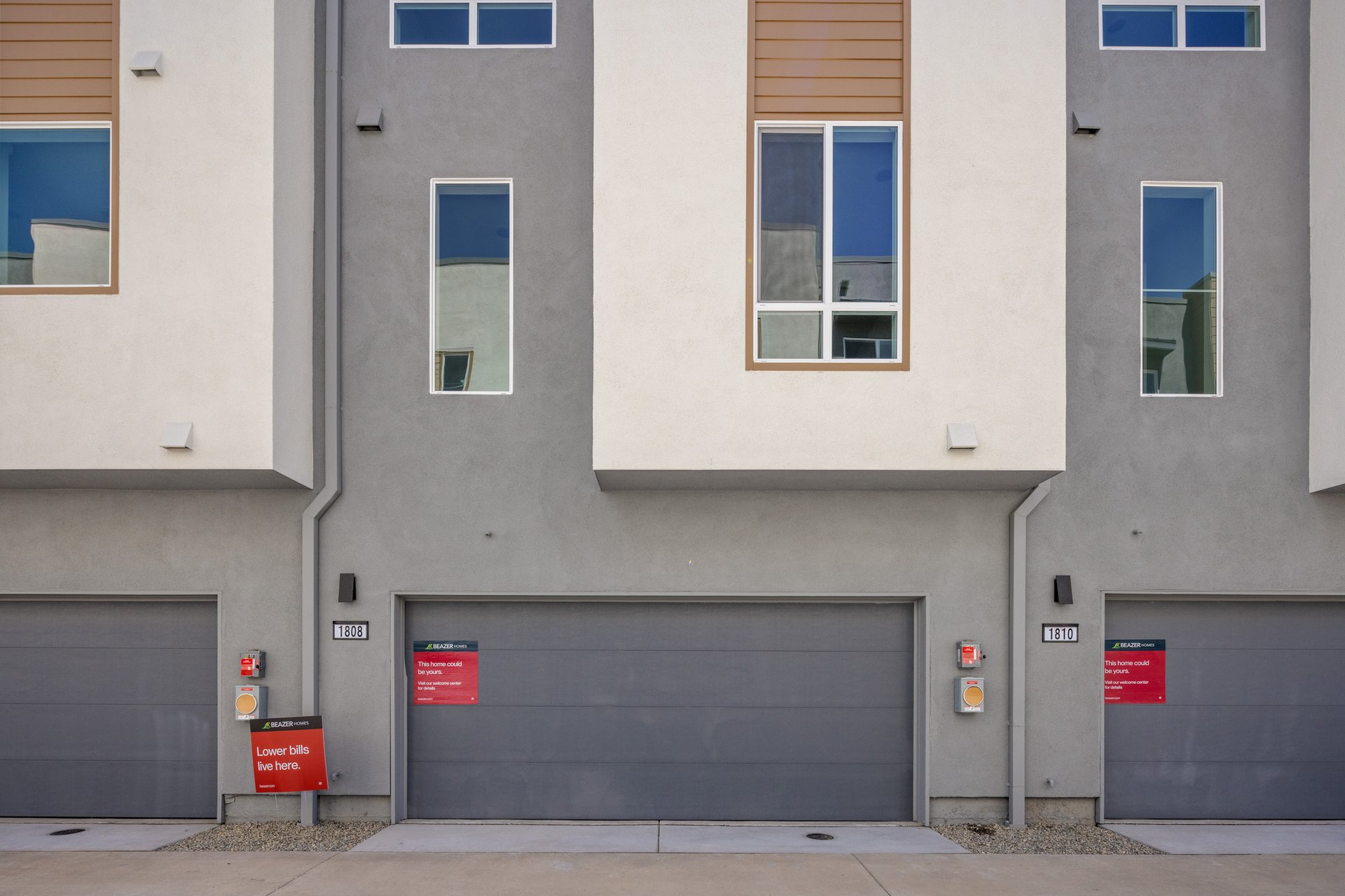 rear exterior of gray condo building with windows and two-car garage