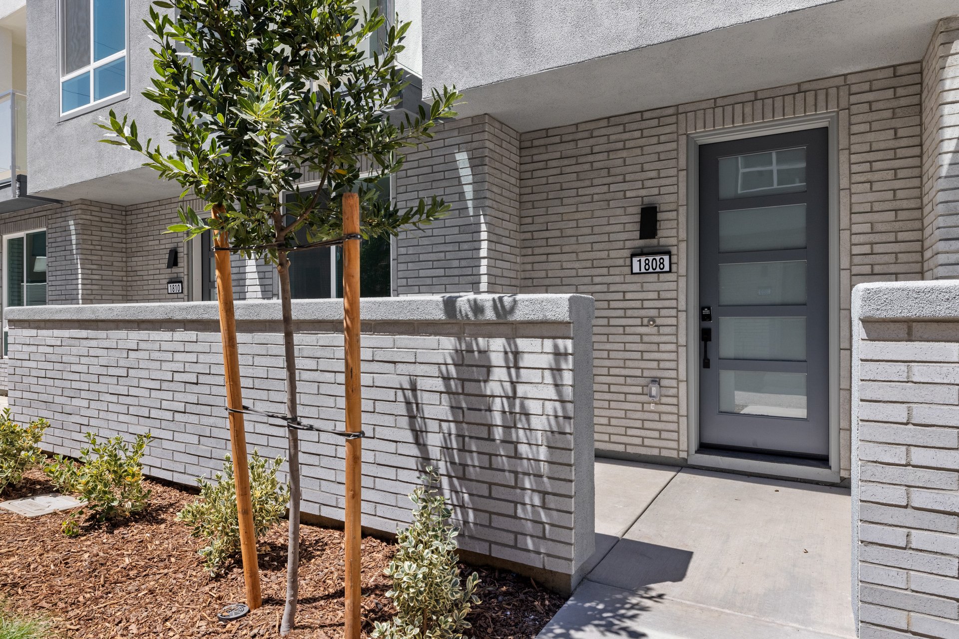 front exterior of condo entrance with gray brick courtyard and black front door