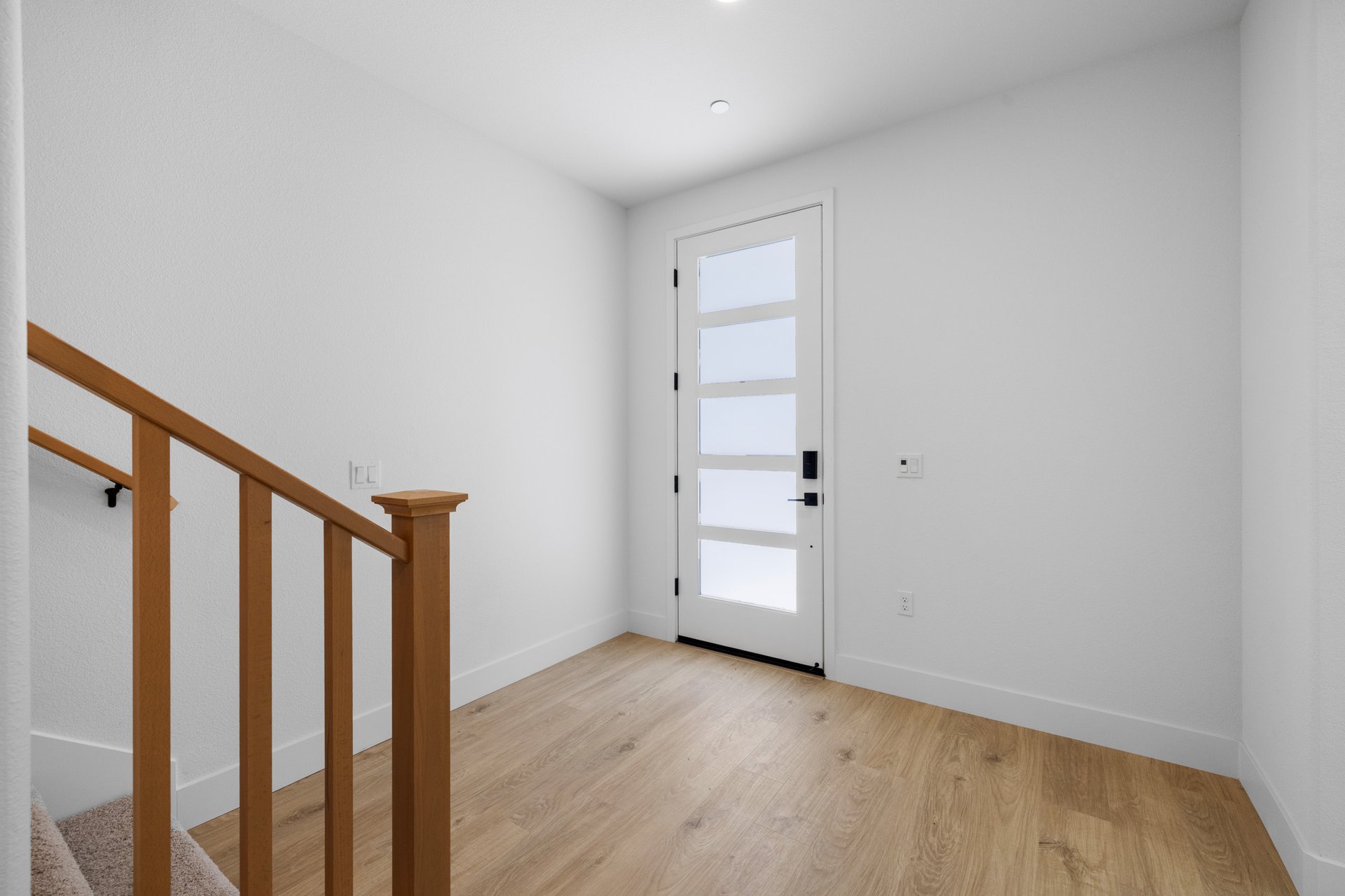 entry foyer with white walls, wood floor, and staircase leading upstairs