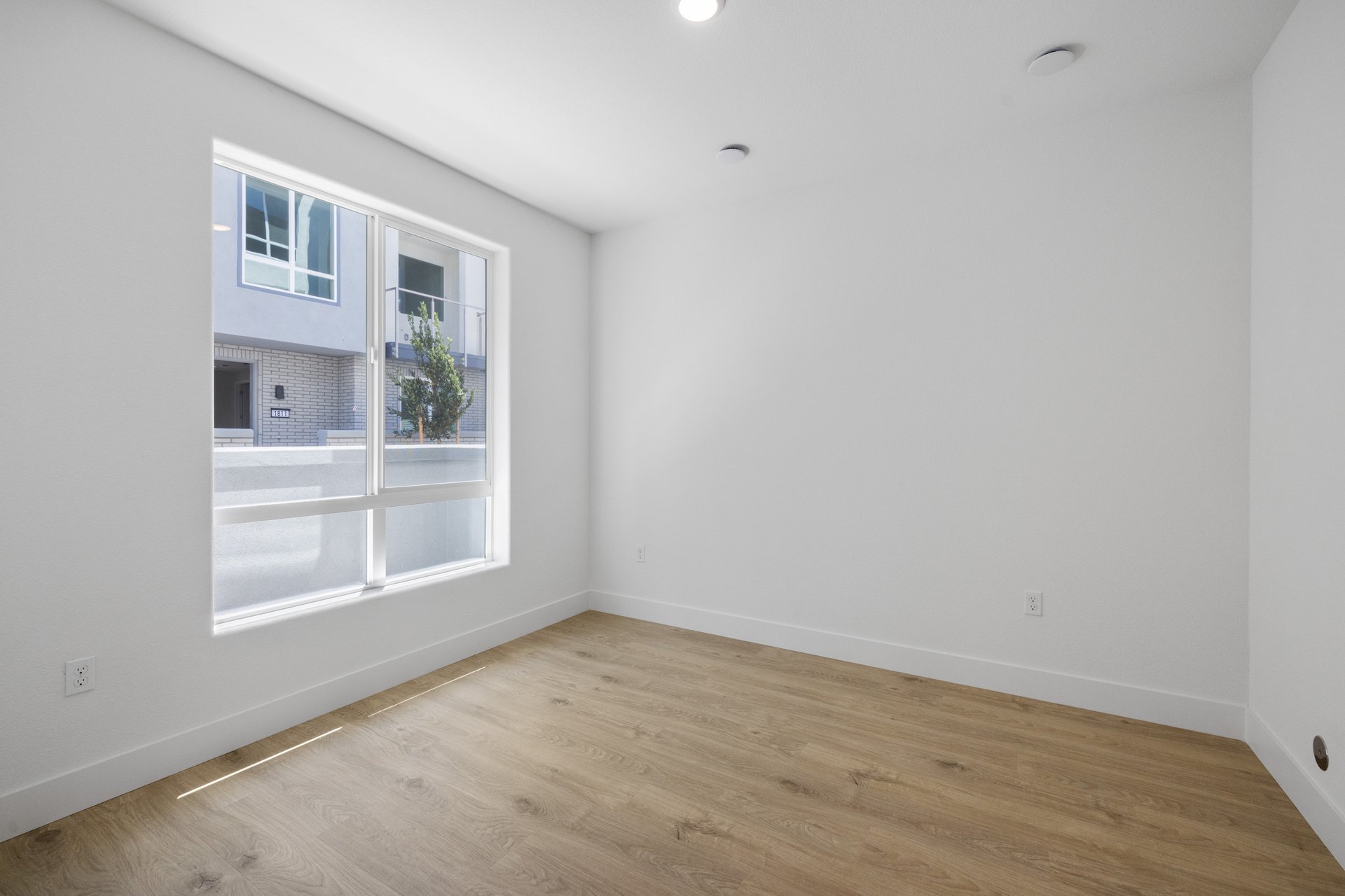 study with wood floor, white walls, large window, and recessed ceiling light