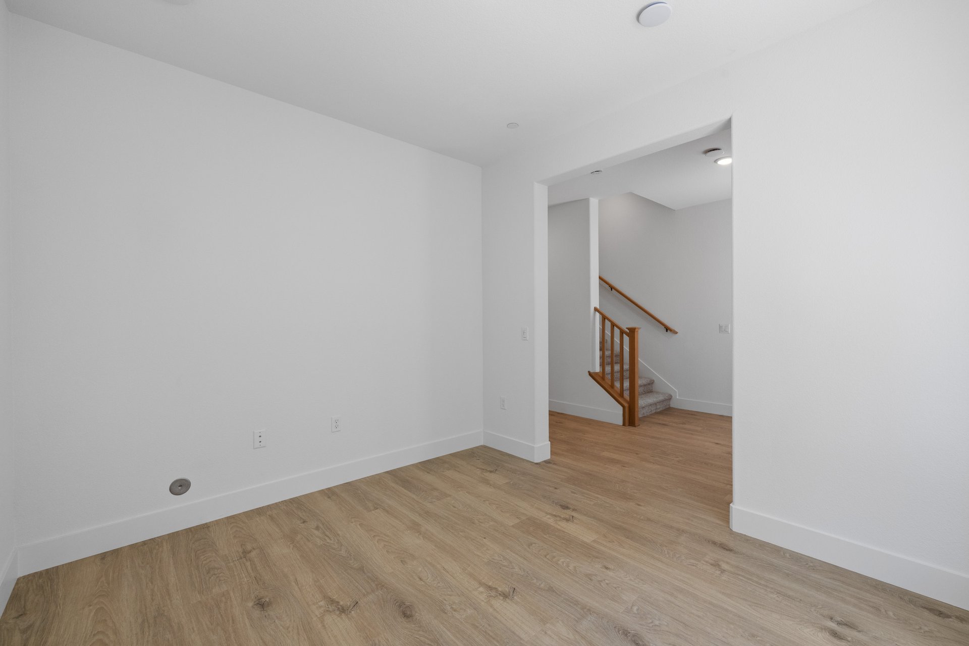 study with wood floors, white walls, and view of front entry foyer