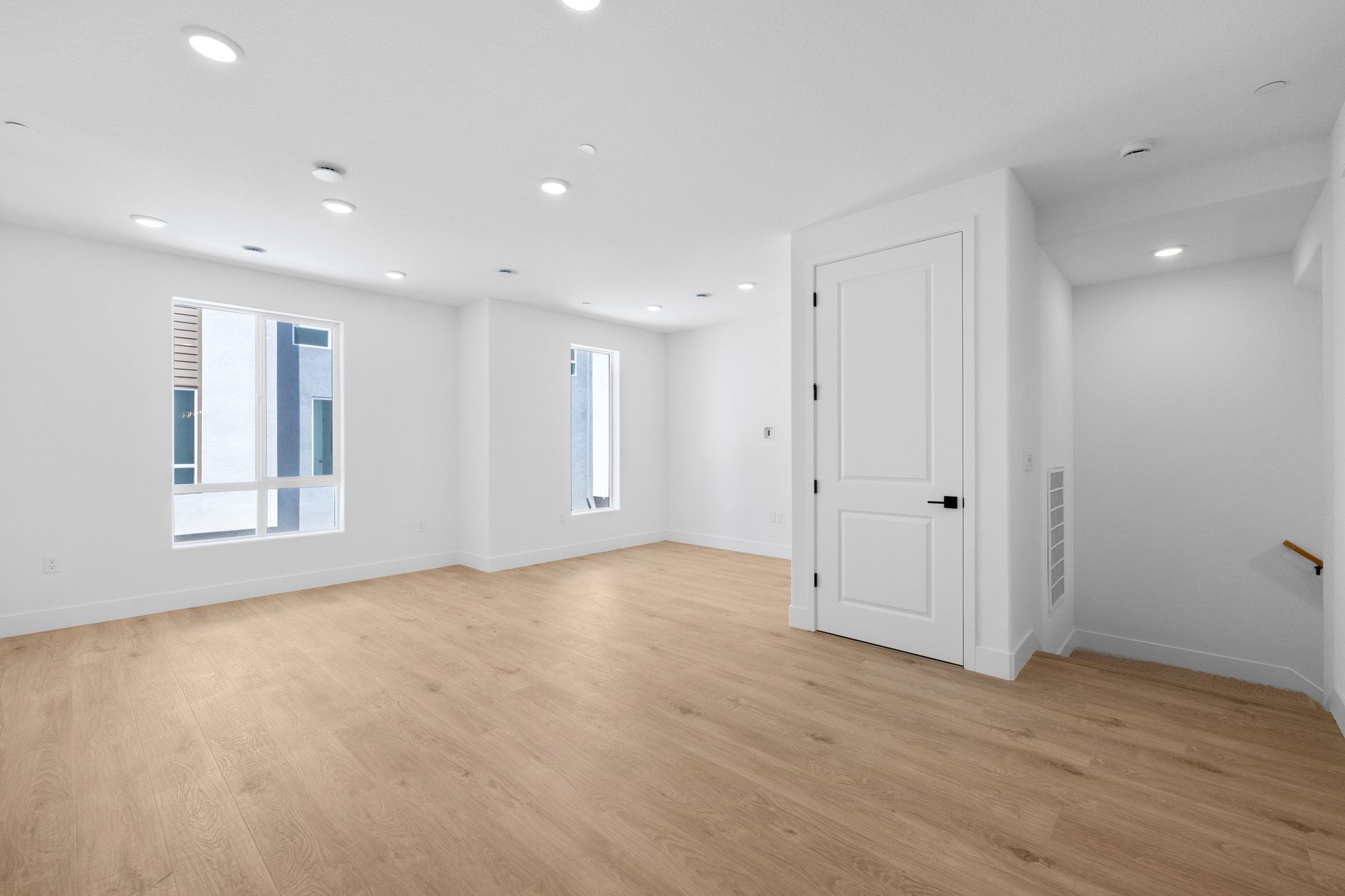 great room with wood floors, white walls, two windows, and view of staircase