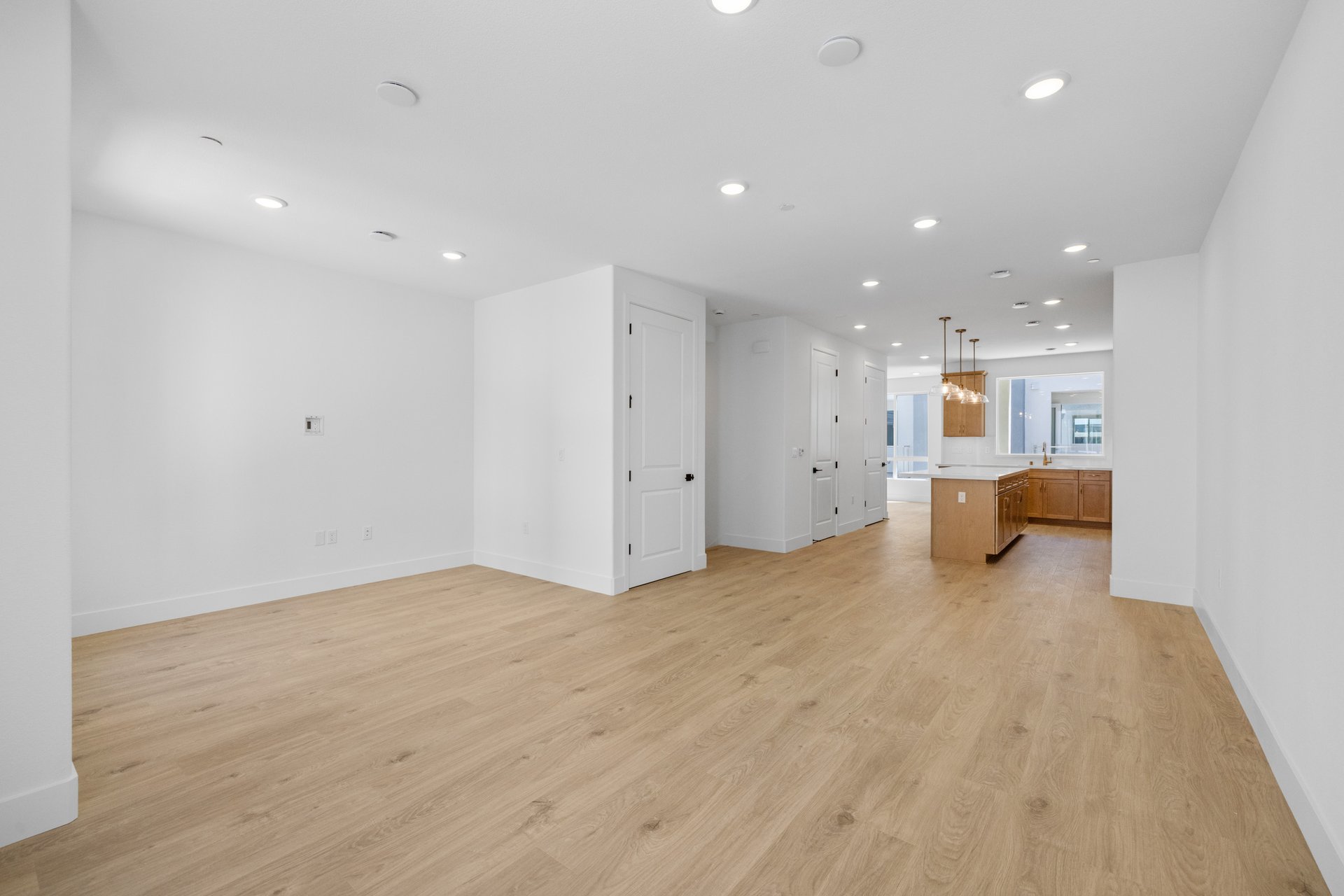 great room with wood floors, white walls, recessed ceiling lights, and view of kitchen