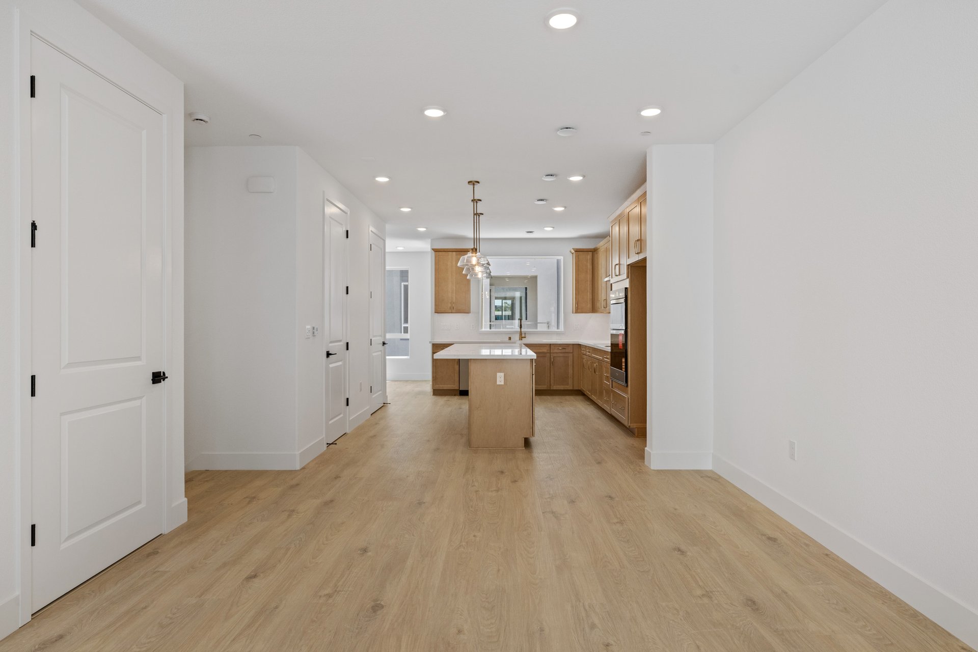 kitchen with wood floors, light wood cabinets, island, and large window above sink