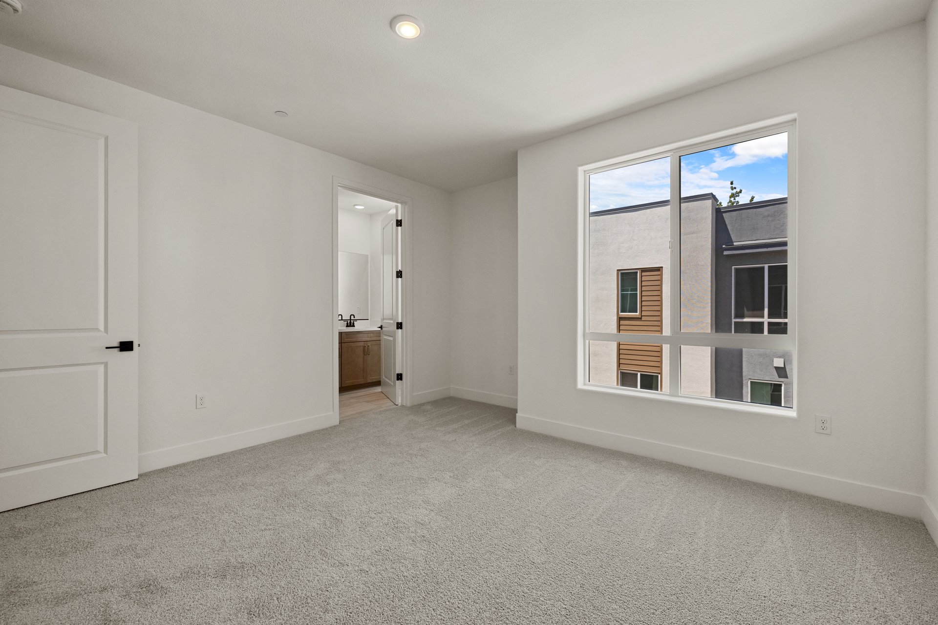 bedroom with gray carpet, large window, white walls, and view of attached bathroom