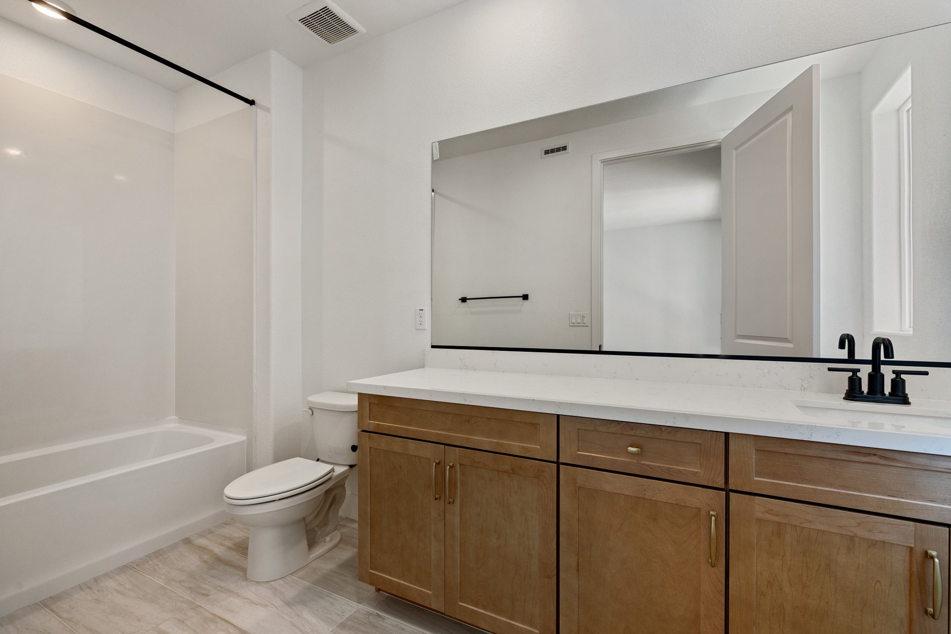 bathroom with wood cabinets, white counters, tan tile floors, and tub with shower overhead