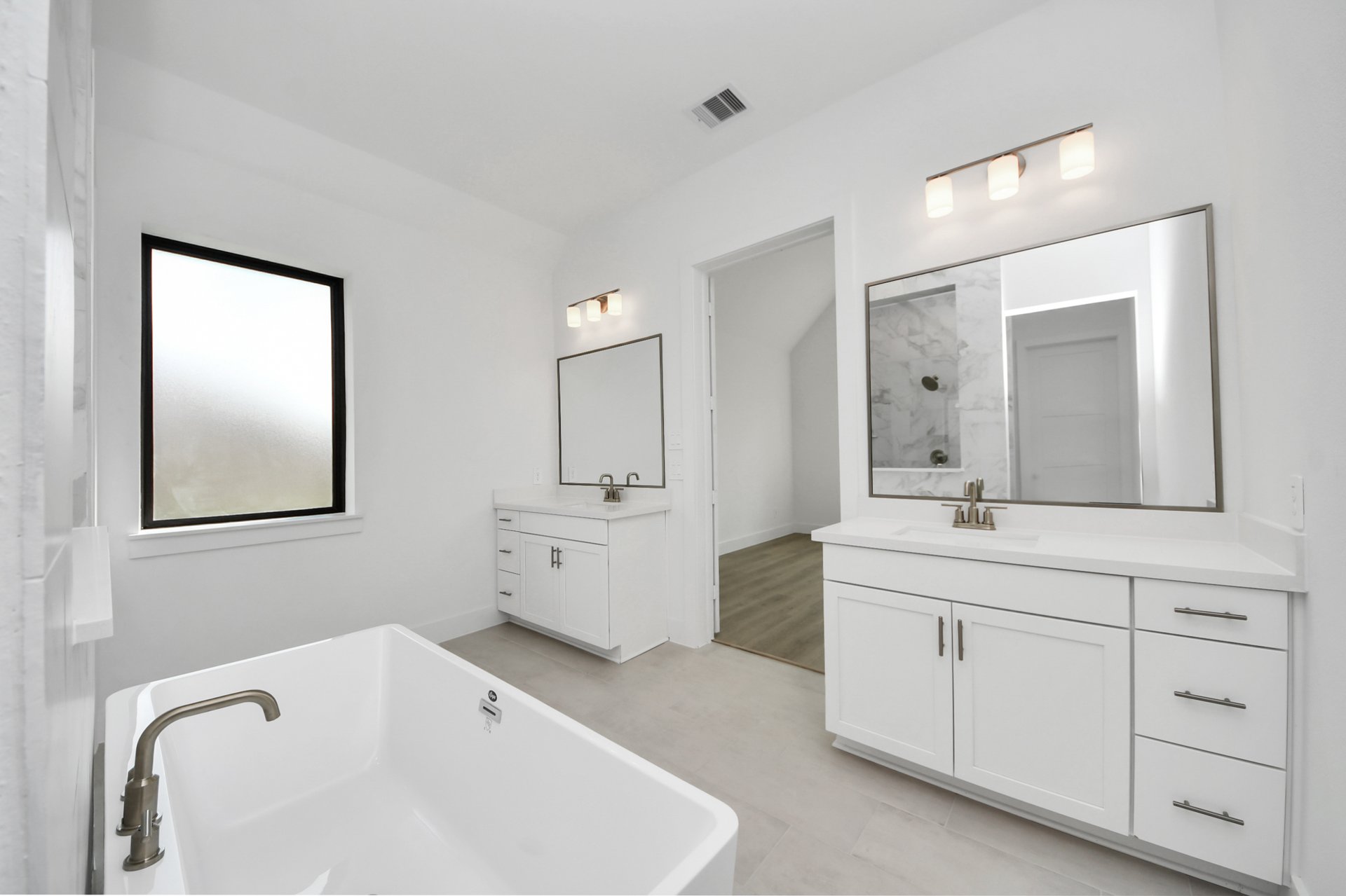 separate sinks with white cabinets and large mirrors