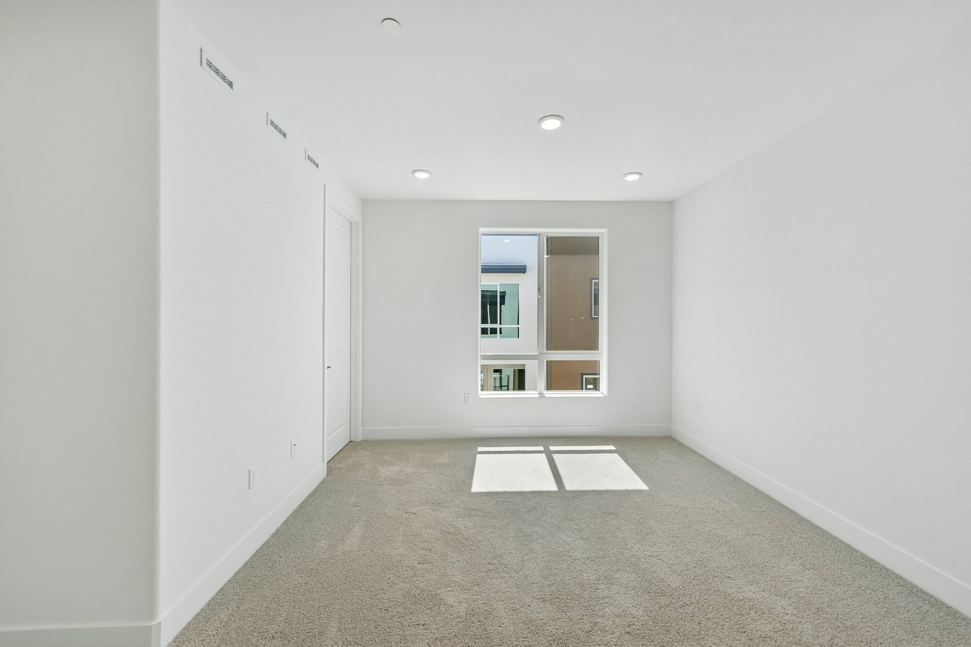 bedroom with tan carpet, white walls, and window