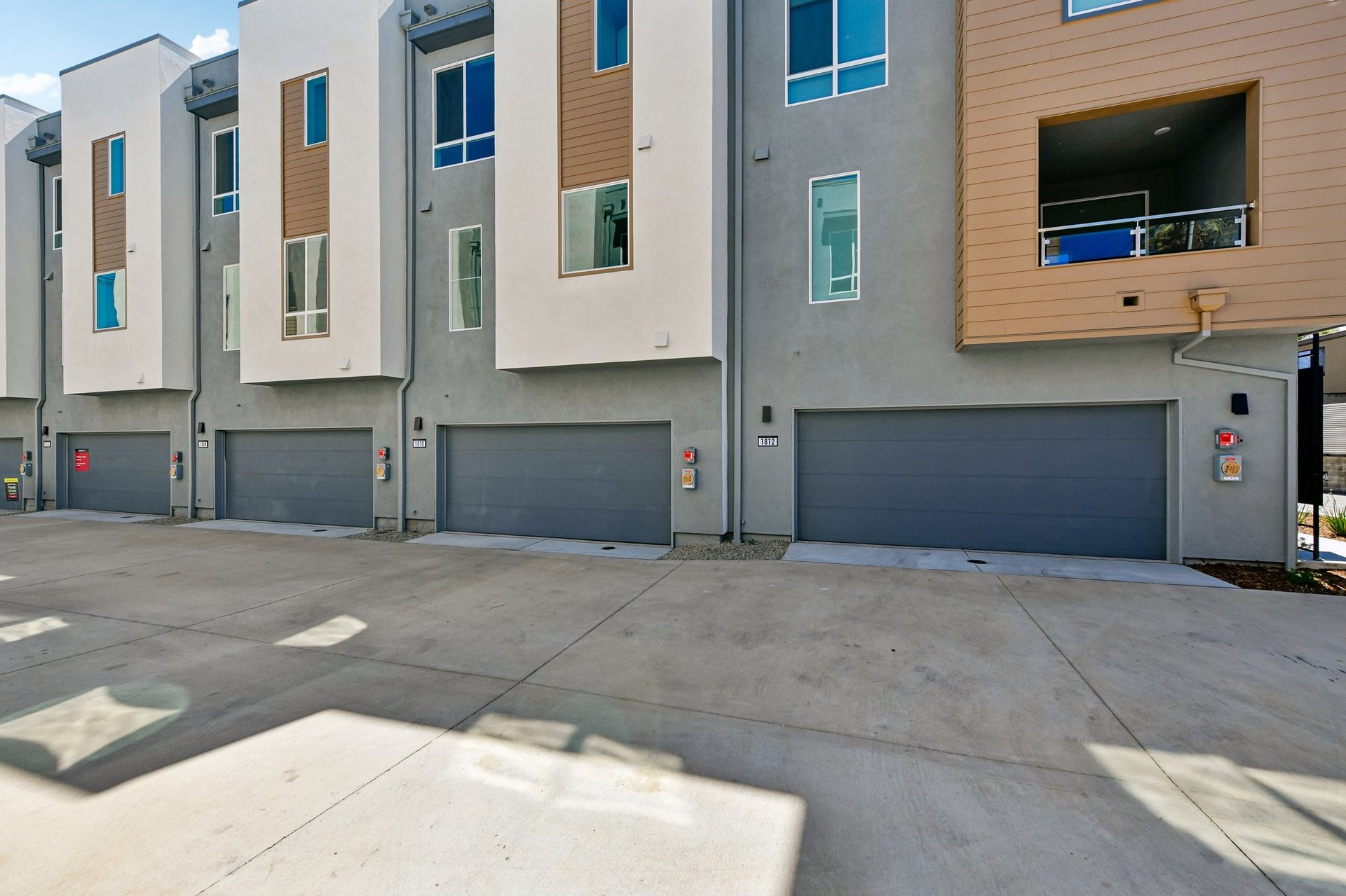 rear exterior of gray and brown condo building with attached two-car garages