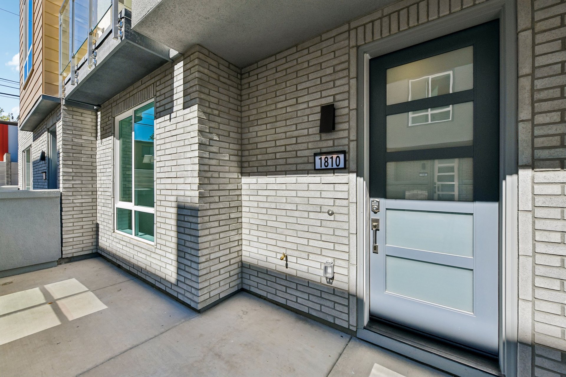 front entry courtyard to condo with gray brick and black front door