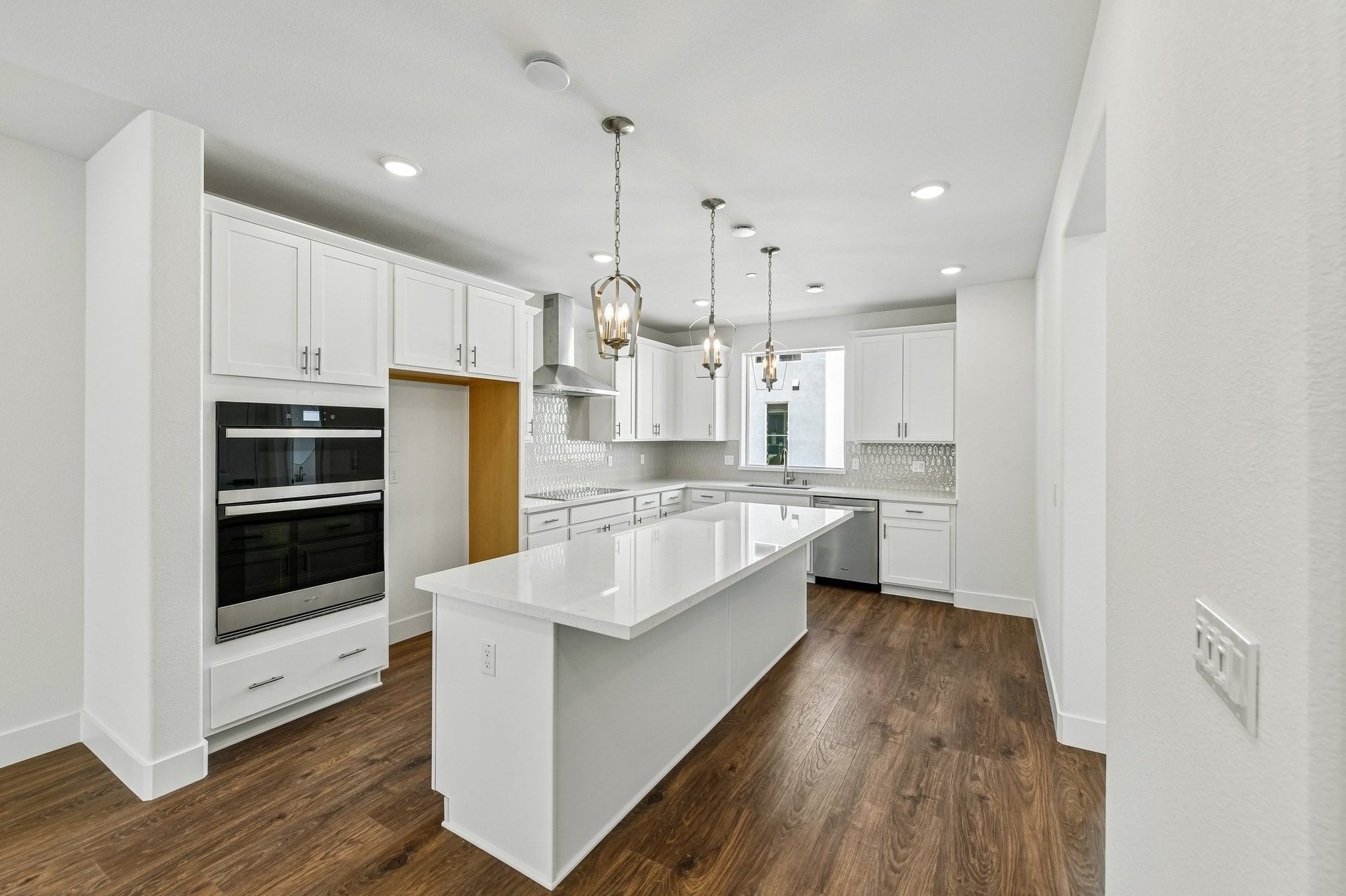 kitchen with wood floors, white cabinets & counters, white walls, and window