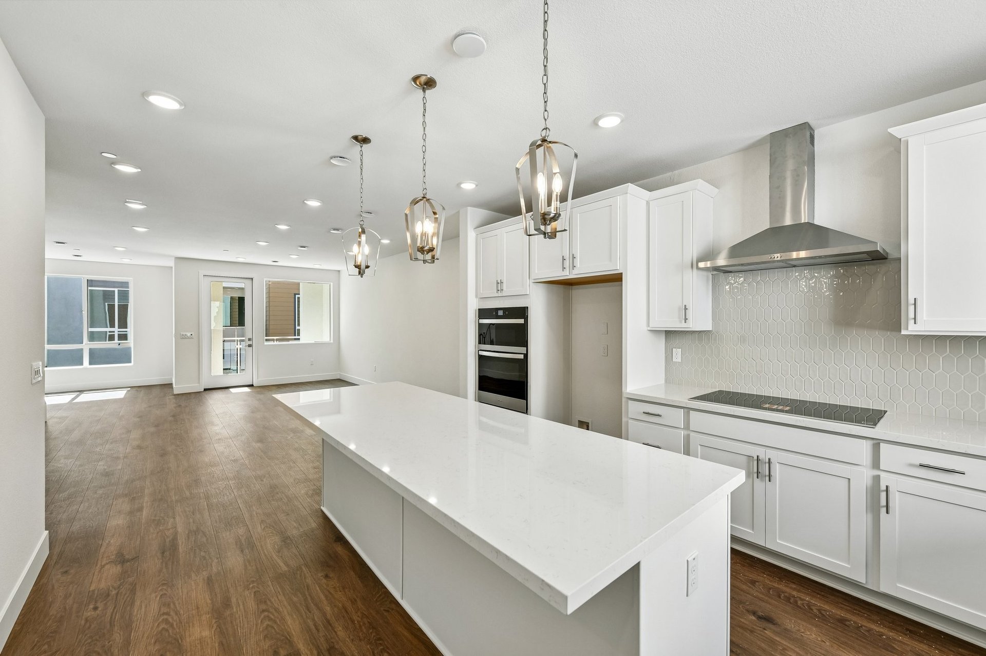 kitchen with white cabinets & counters, wood floors, and three hanging pendant lights over island