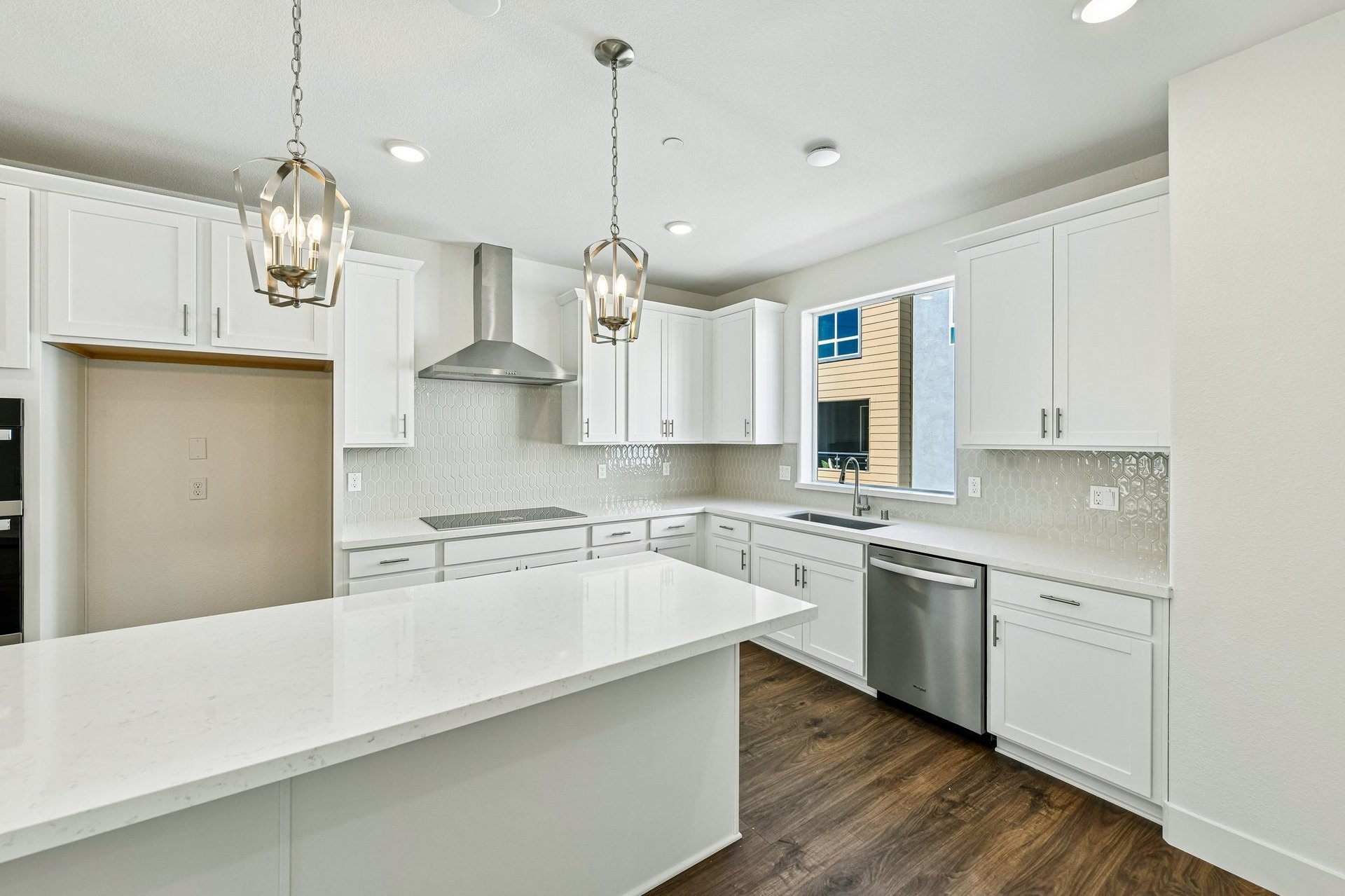 kitchen with white cabinets & counters, wood floors, island, stainless steel appliances, and window above sink