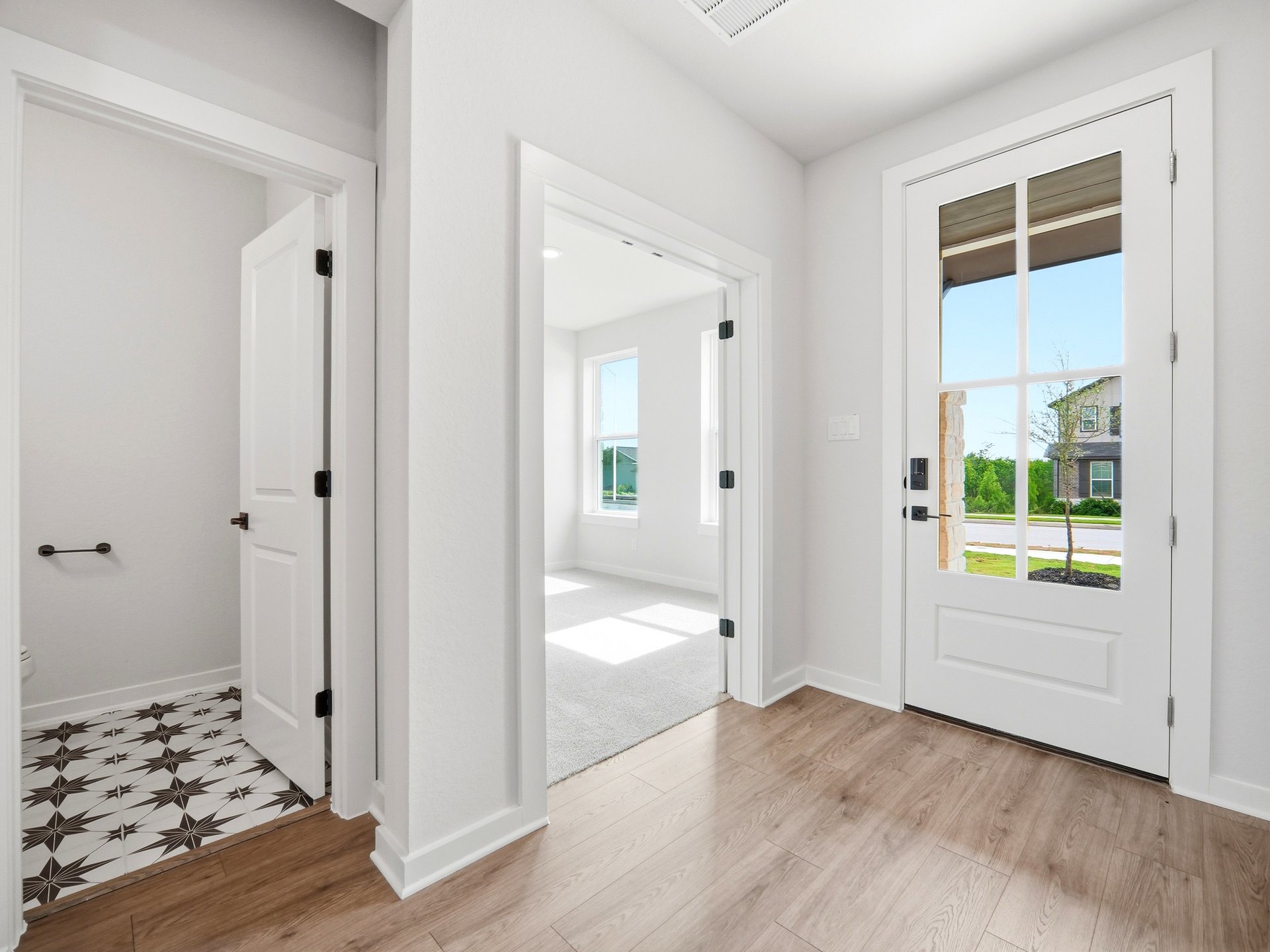 foyer with brown flooring, door and pendant lighting